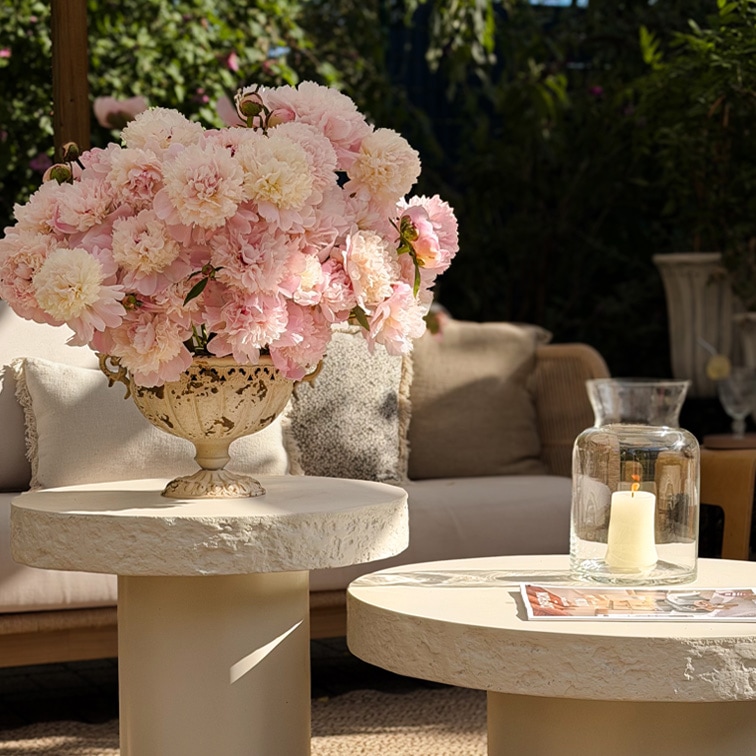 Decoratief boeket roze pioenrozen in keramische vaas op lichte tuintafel met natuurlijk licht