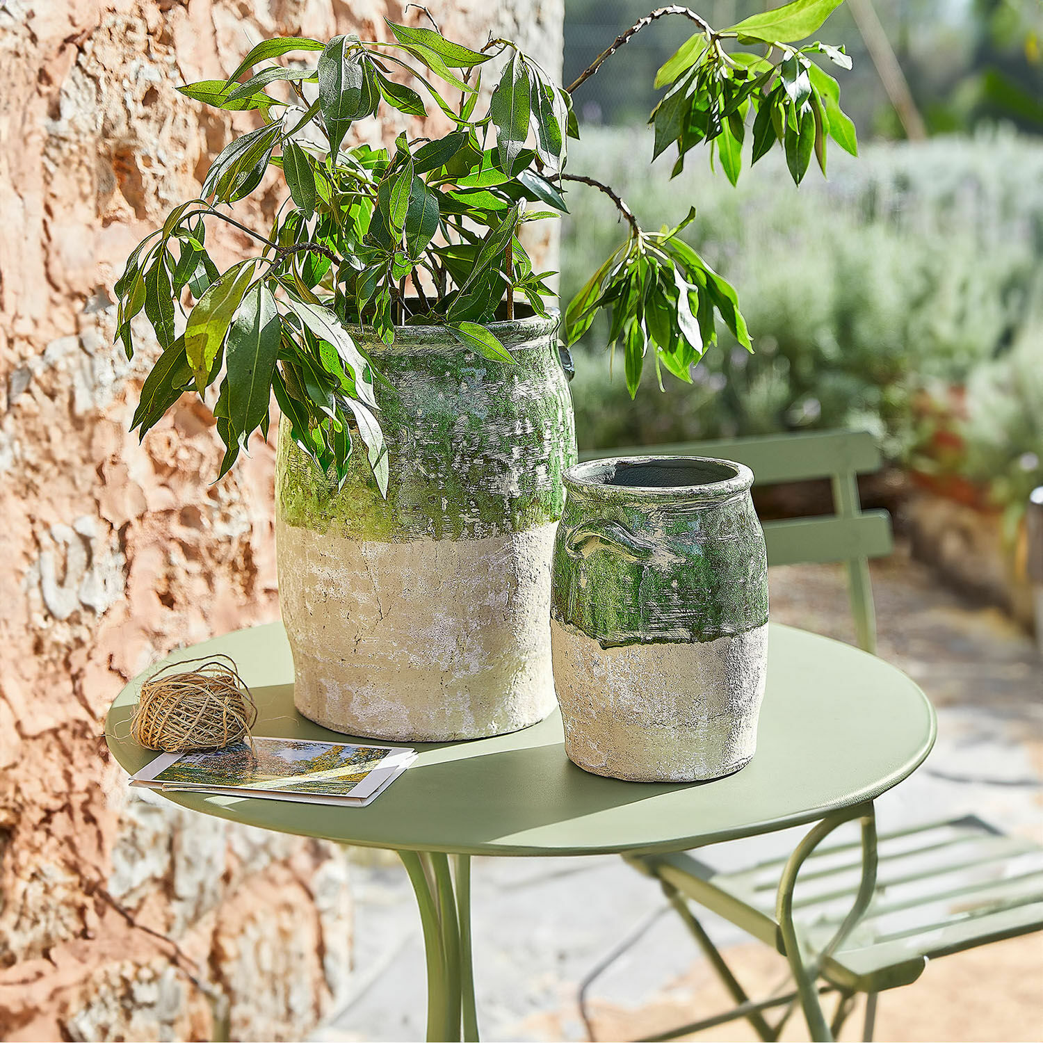 Vaas set van 2 Reefton Twee keramische vazen in groen-beige op een groene tuintafel met plant en ansichtkaarten