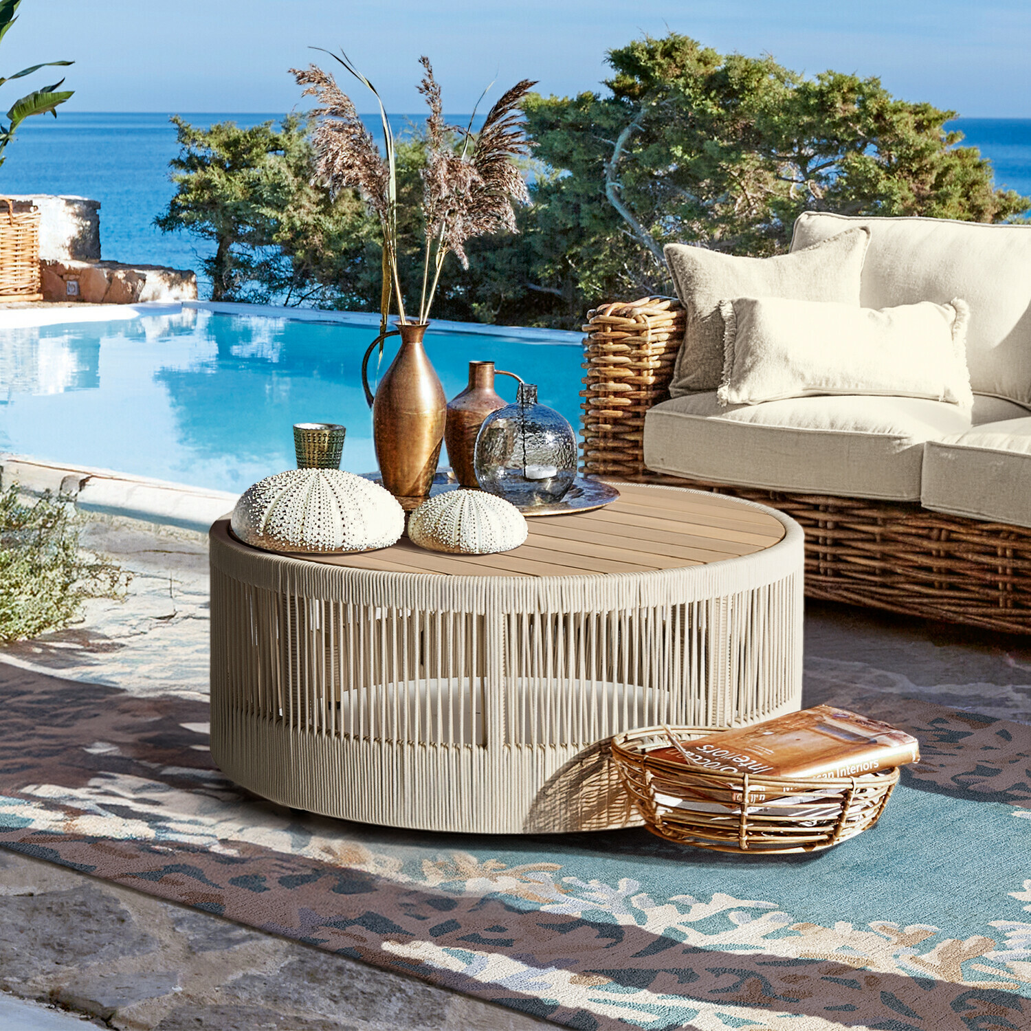 Table basse Delor Table basse ronde en corde beige et bois sur terrasse près de la piscine avec décorations et canapé en osier