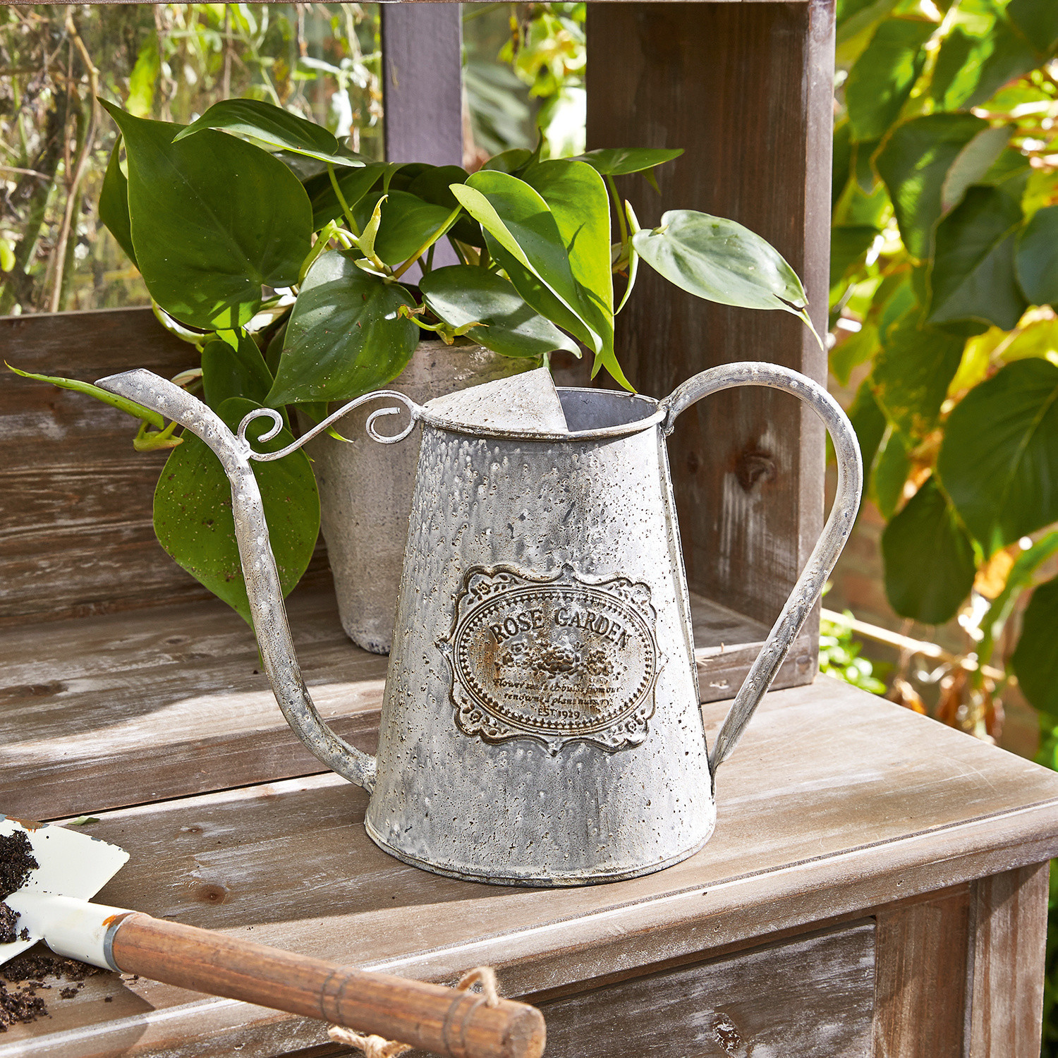 Gieter Rose Garden Vintage metalen gieter met Rose Garden opschrift op houten tafel in tuin