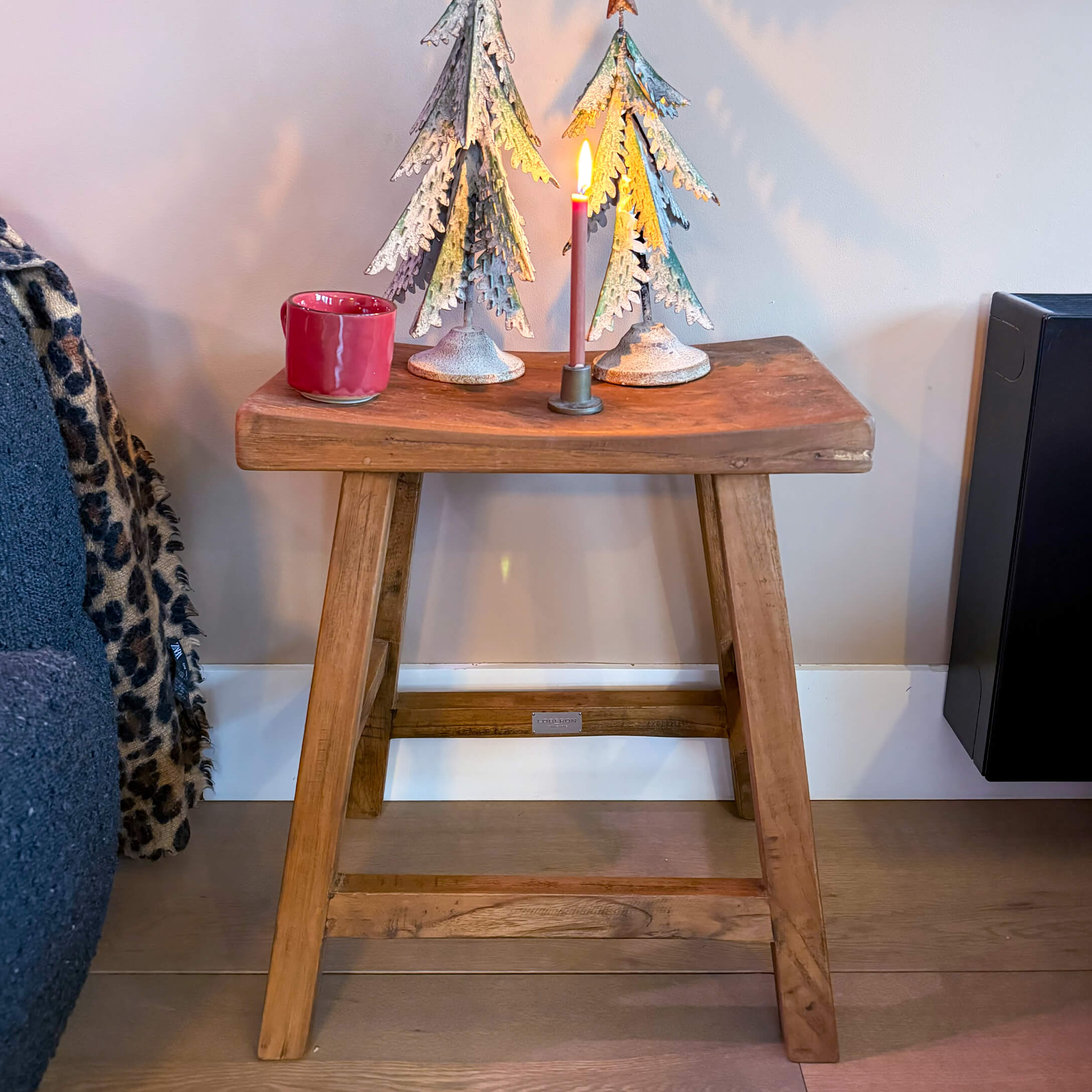 Tabouret en bois avec décorations sapins en métal et bougie allumée sur le dessus, style industriel