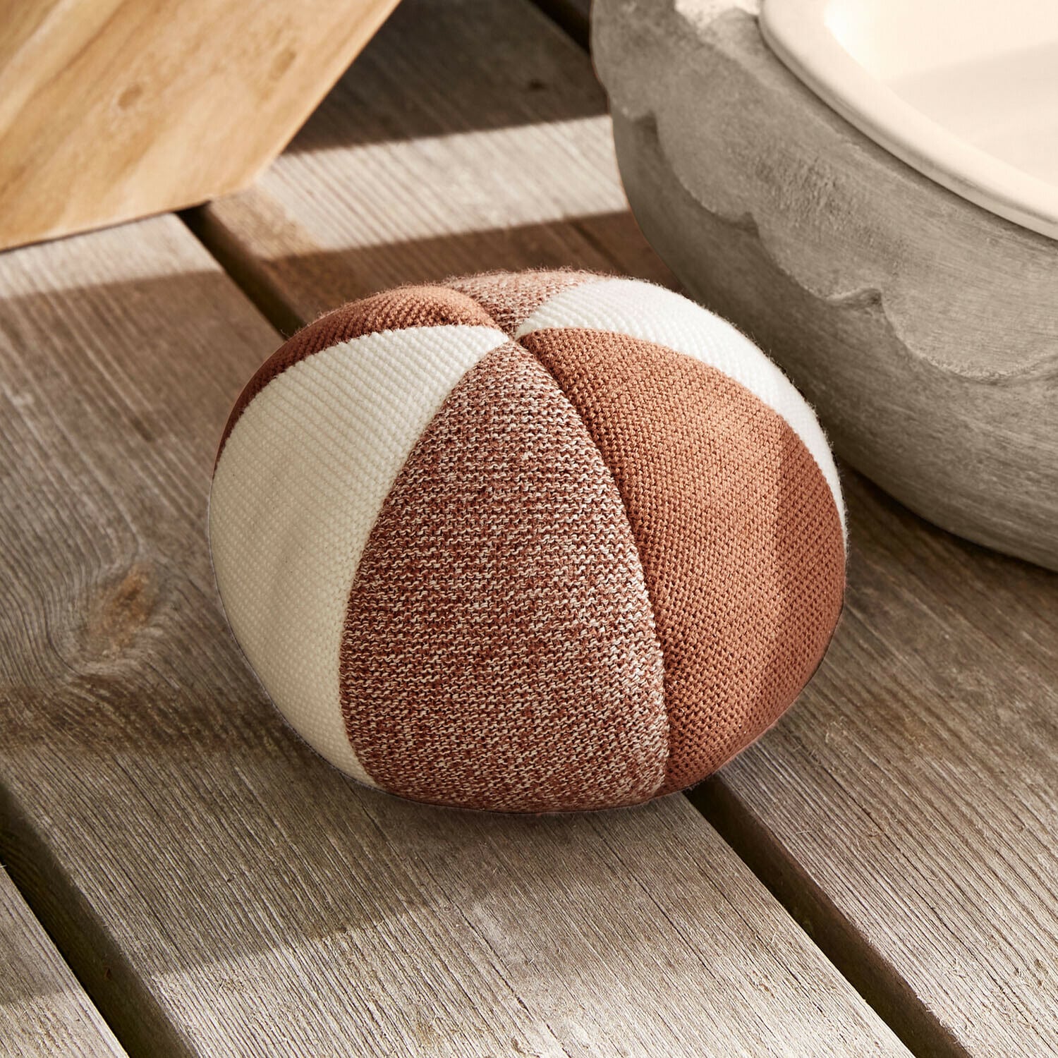 Coussin rond en tissu rayé marron et blanc posé sur un sol en bois clair