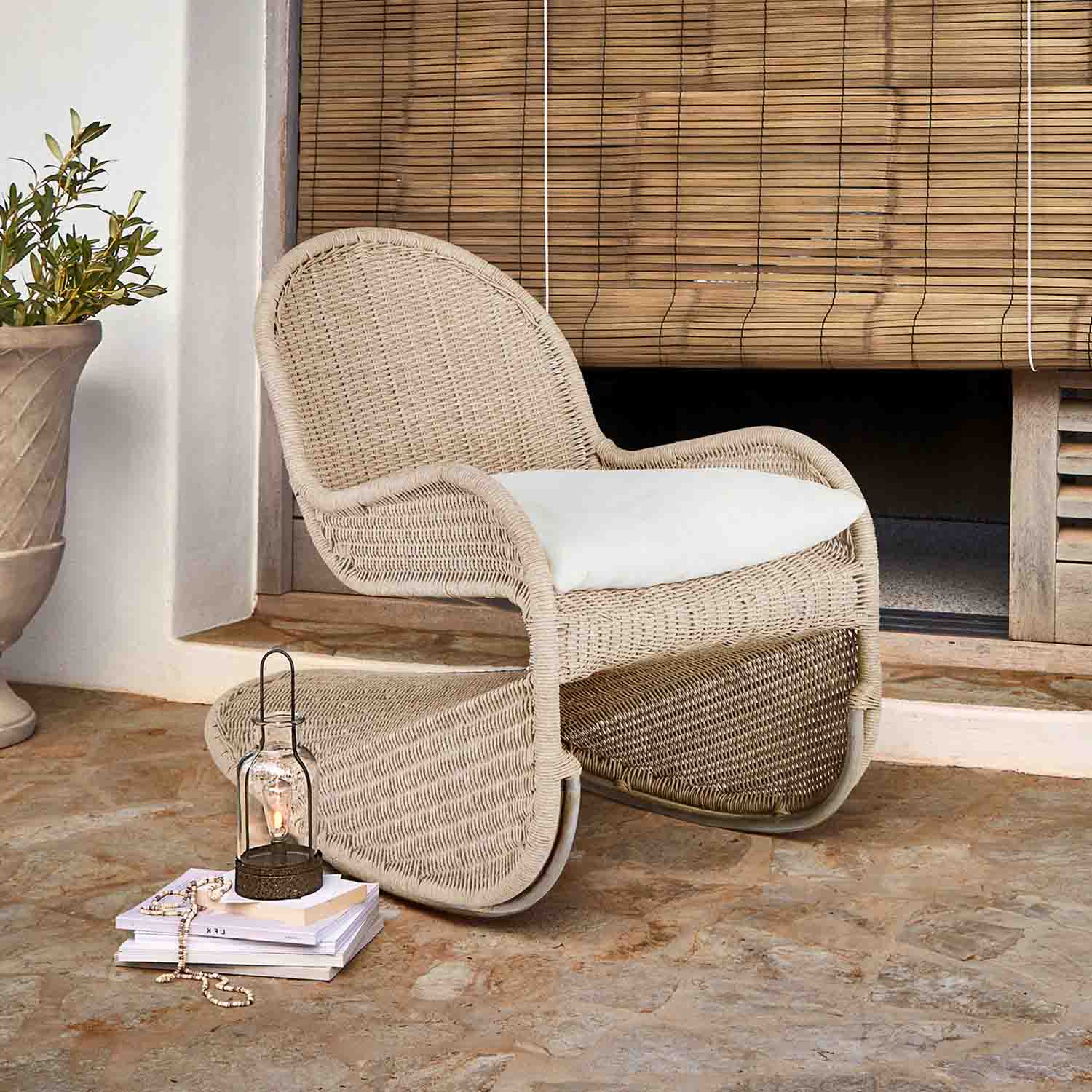 Fauteuil à bascule en rotin clair avec coussin blanc, parfait pour la détente en terrasse ou jardin