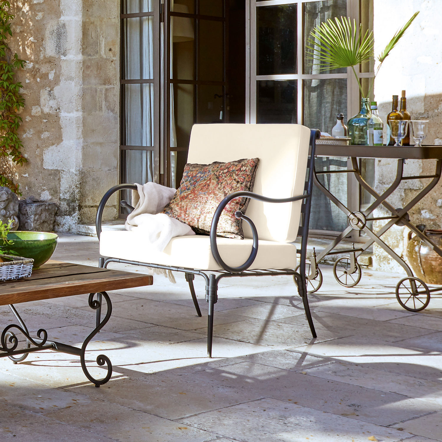 Fauteuil Neret Canapé de jardin en métal avec coussins crème et coussin décoratif sur patio en pierre