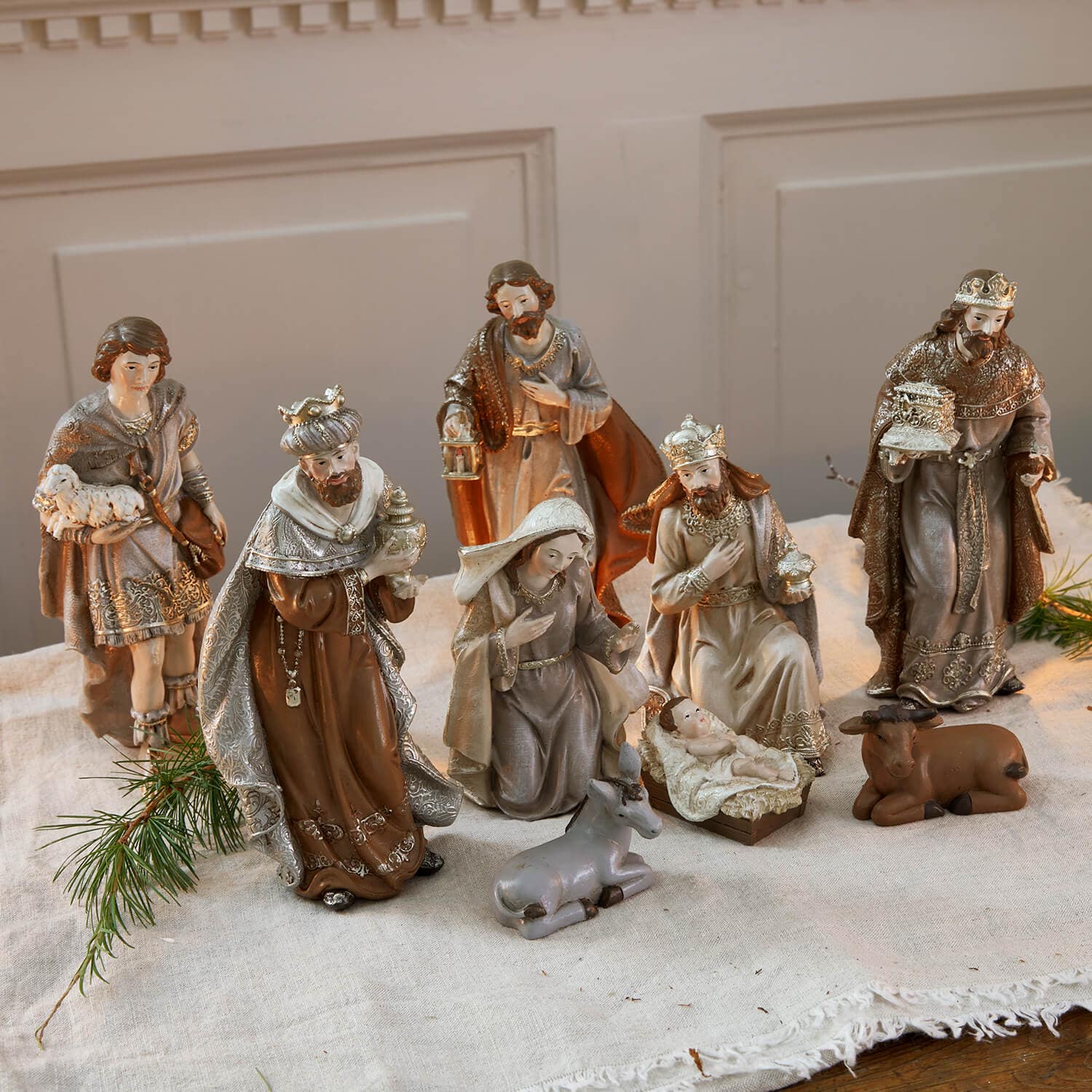 Ensemble de figurines de crèche en résine marron et gris disposées sur une nappe en lin pour décoration de Noël