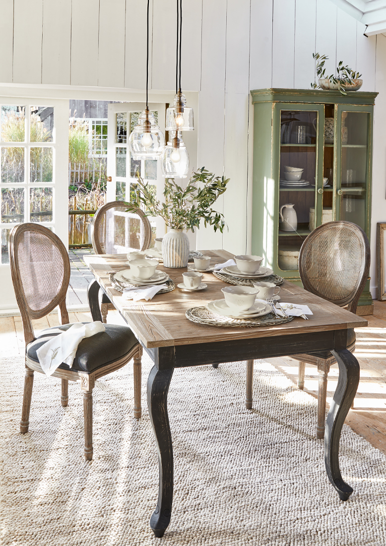 Salle à manger avec table en bois et chaises en osier vintage, lumière naturelle et décorations élégantes