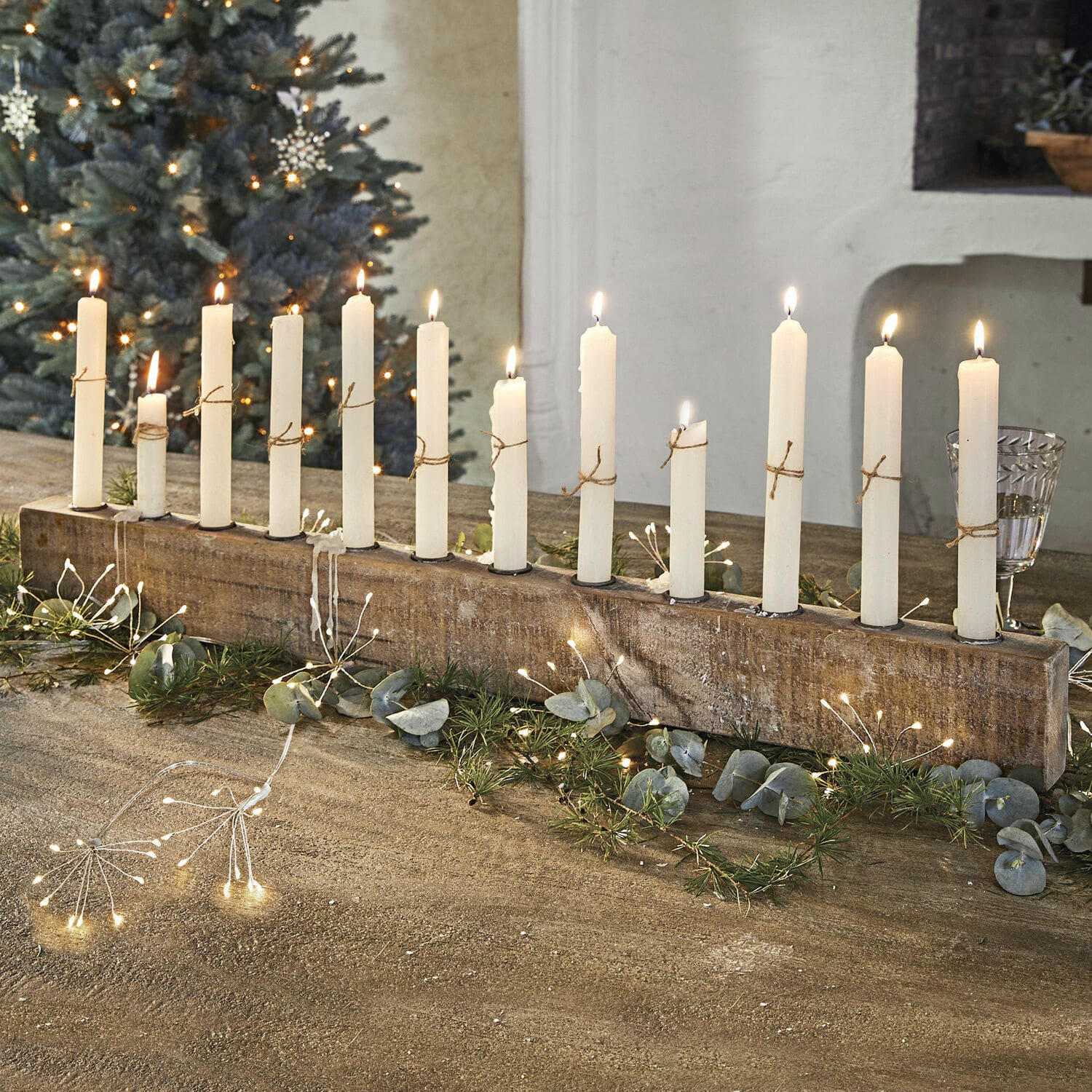 Bougeoir Nicky Bougeoir en bois avec 12 bougies blanches, décoré de branches vertes et guirlandes lumineuses LED
