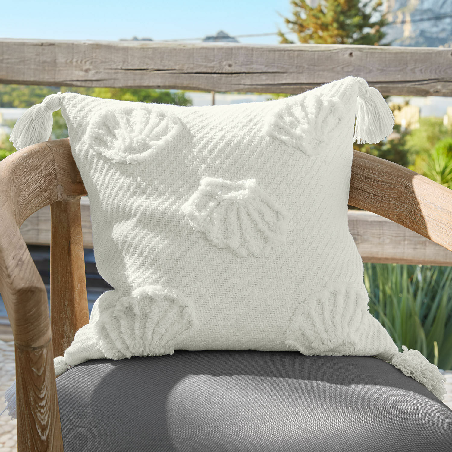 Witte decoratieve katoenen kussen met schelpmotieven en kwastjes op de hoeken