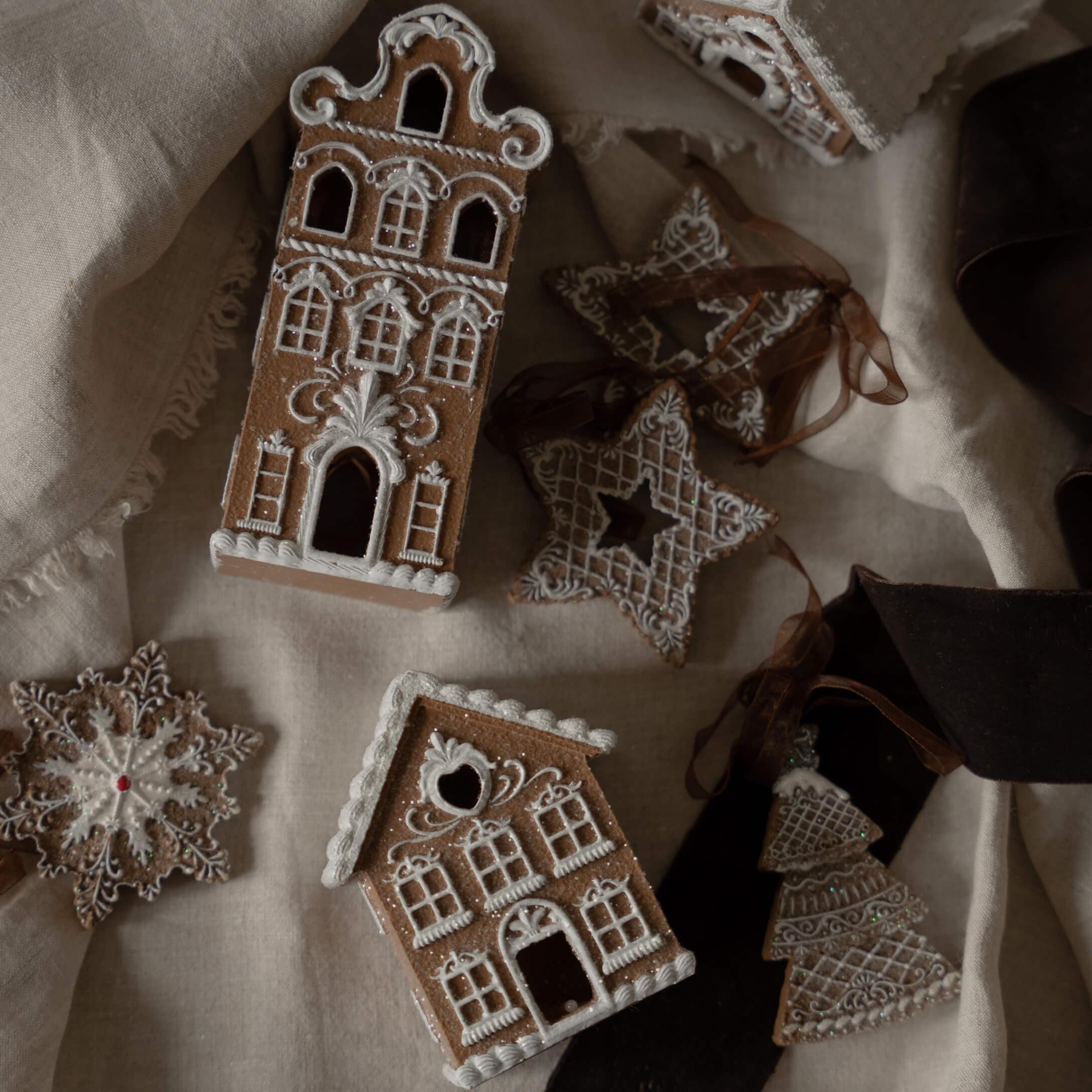 Maisons et étoiles en pain d'épices décorées de glaçage blanc sur tissu en lin, décorations de Noël