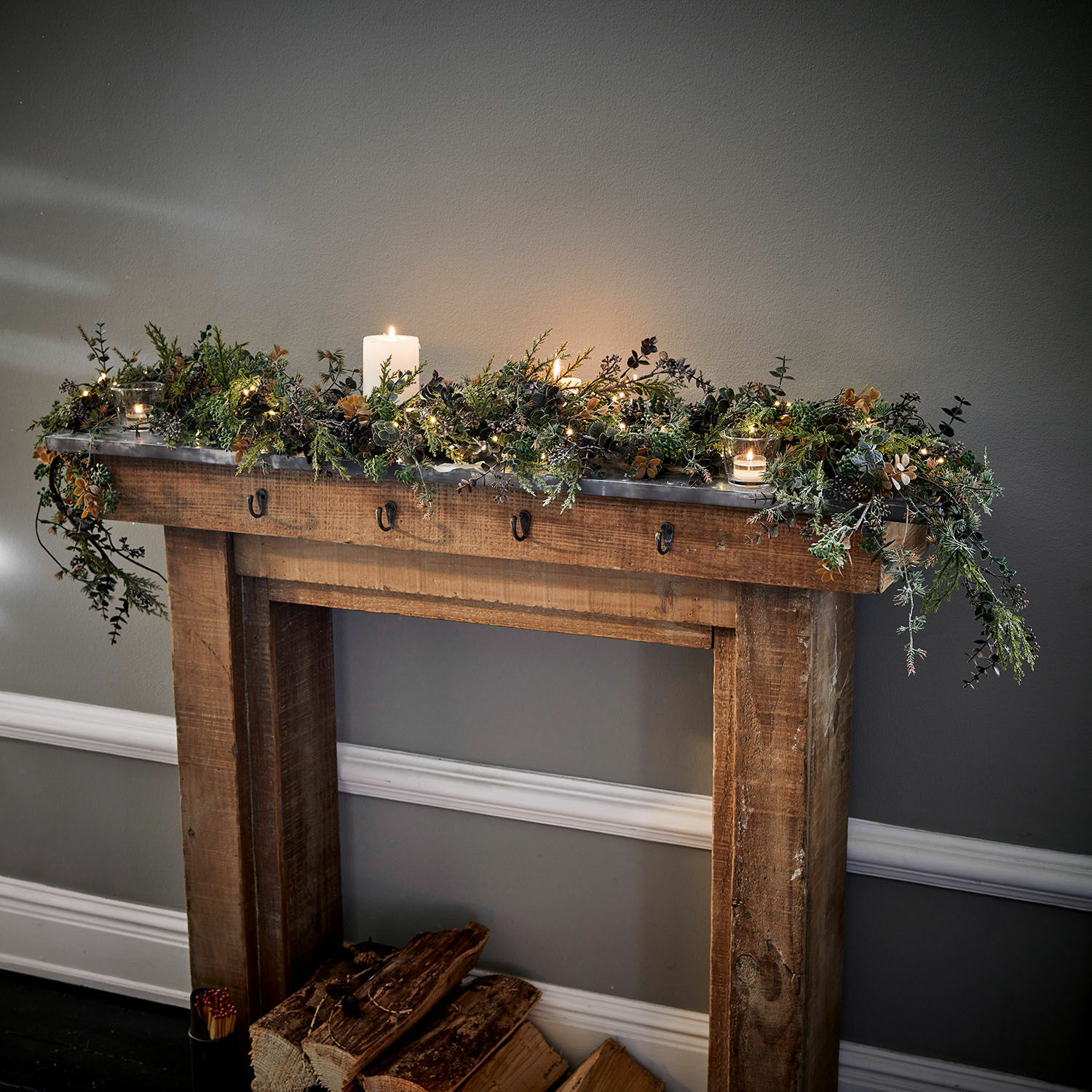 Guirlande Nell Cheminée en bois décorée de branches vertes et bougies, décoration intérieure hivernale chaleureuse