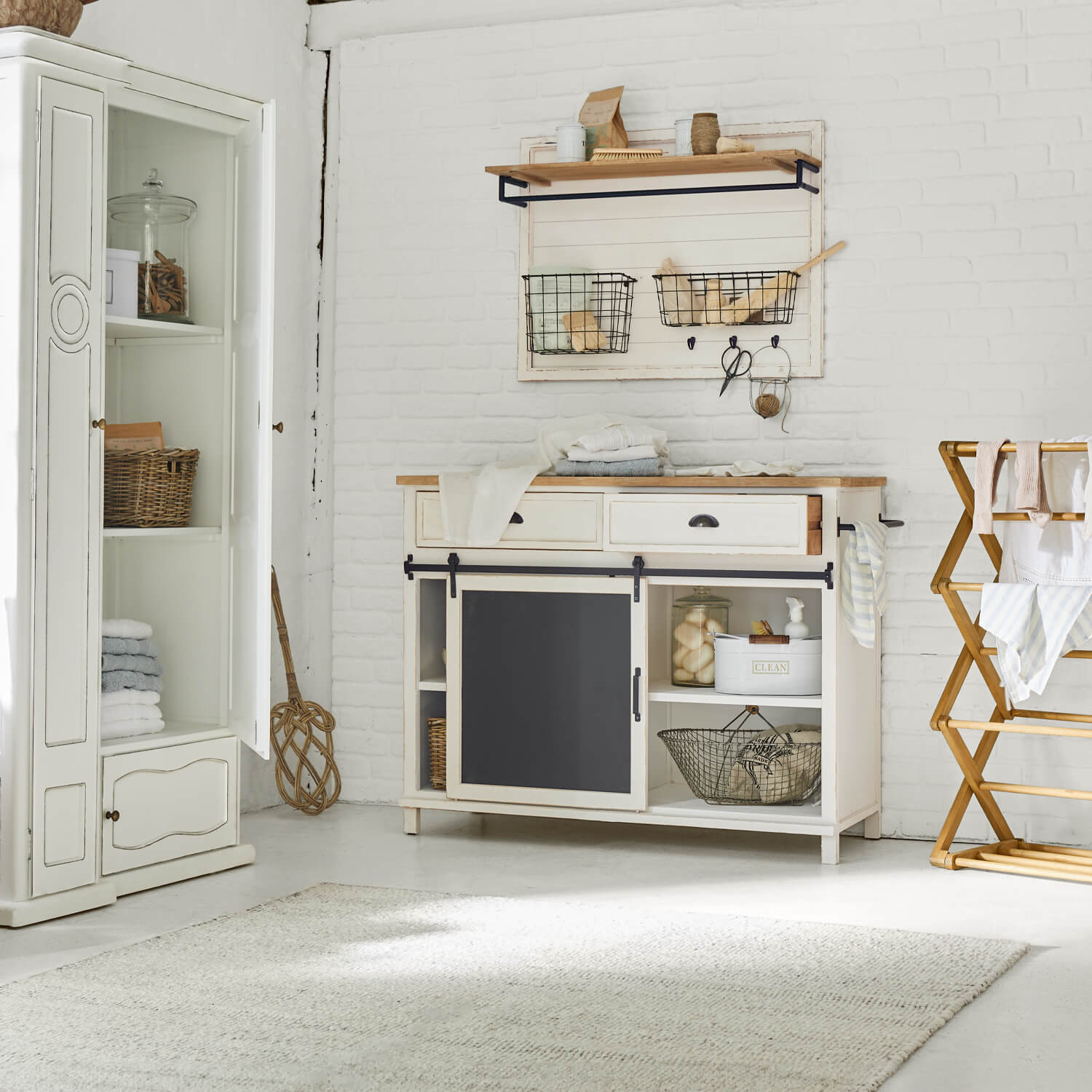 Witte houten dressoir met zwart schoolbord en wandplank met metalen manden in vintage stijl