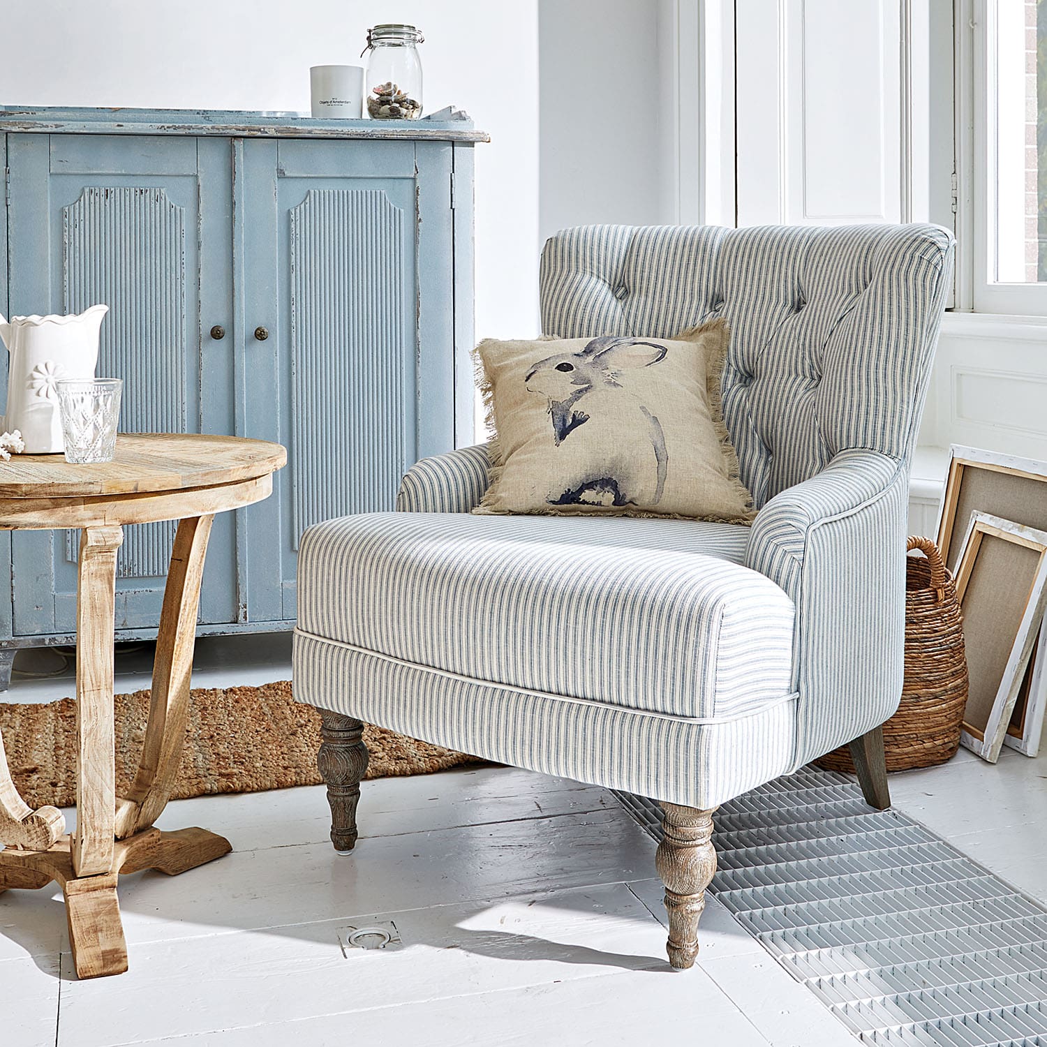 Fauteuil rayé avec pieds en bois et coussin lapin dans un intérieur lumineux et chaleureux