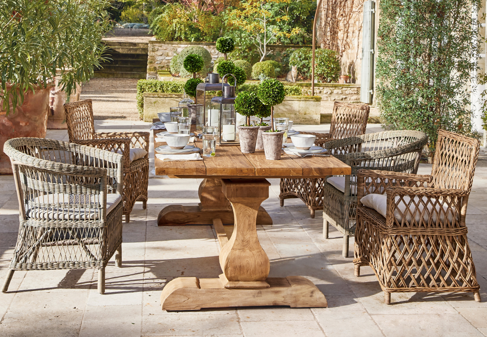 Houten tuintafel met rotan stoelen en planten decoratie op mediterrane terras