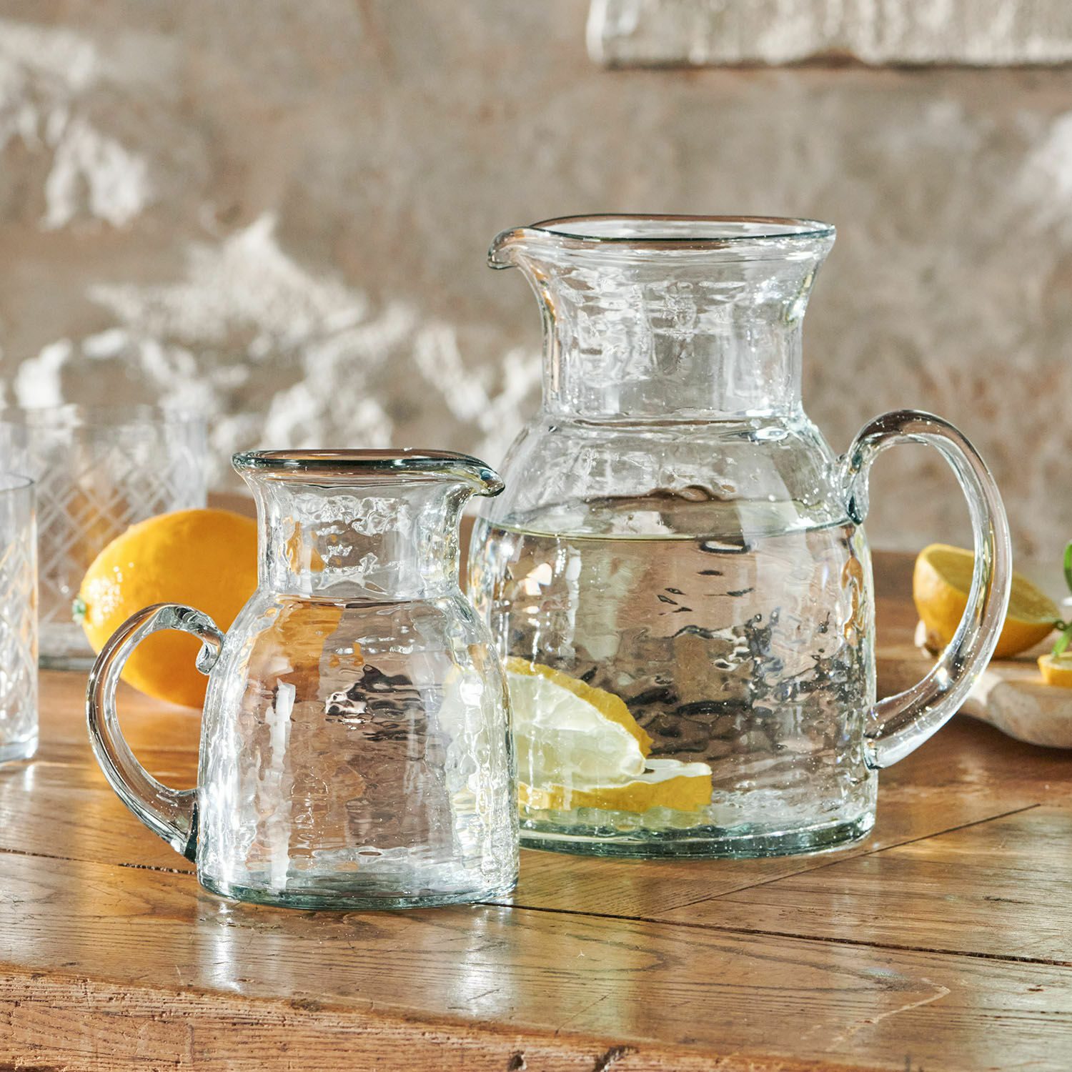 Lot de 2 pichets Zamirah Carafes en verre transparent avec eau et tranches de citron sur une table en bois rustique