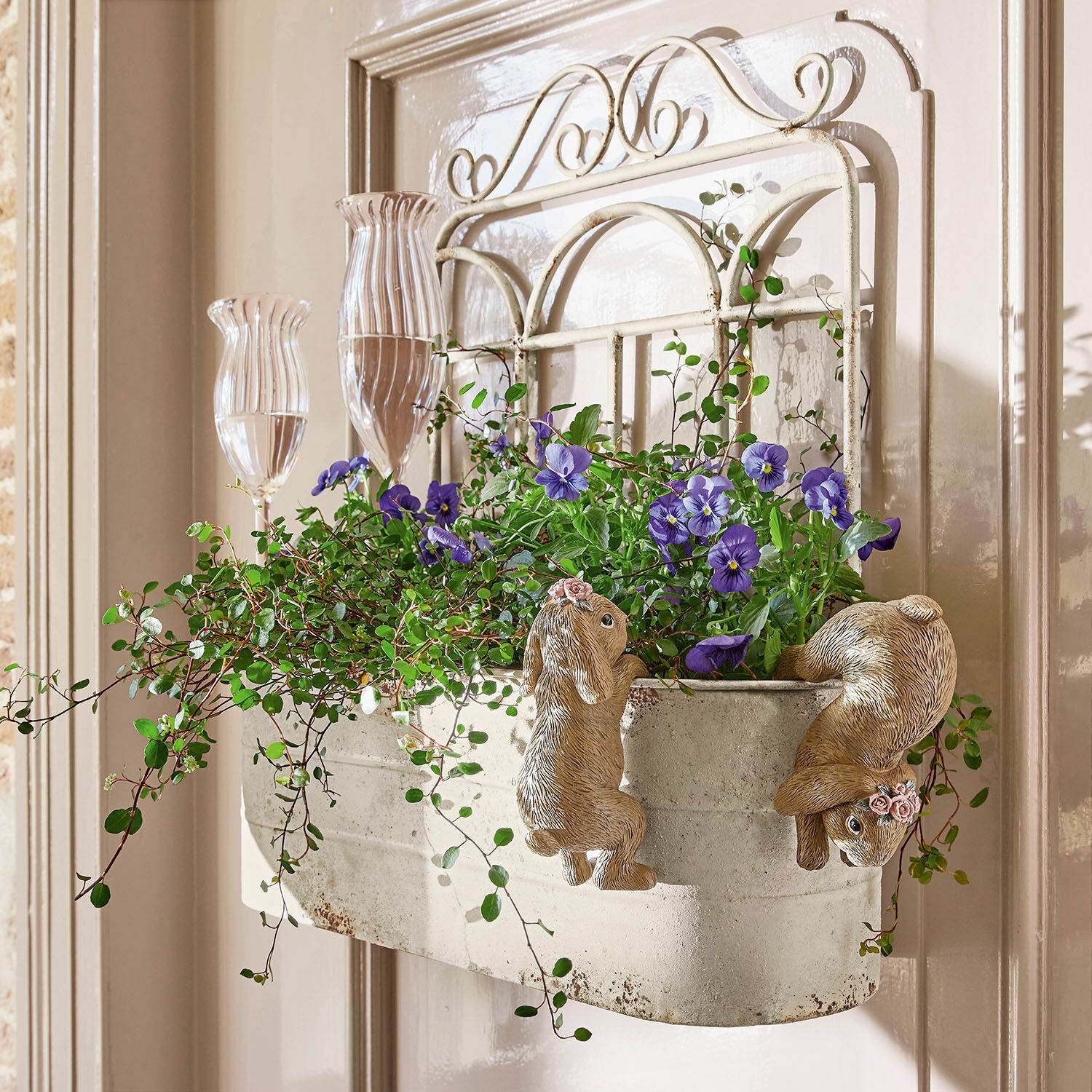 Plantenbak Marwin Metalen wandbloempot met konijnendecoratie en paarse bloemen tegen lichte deur
