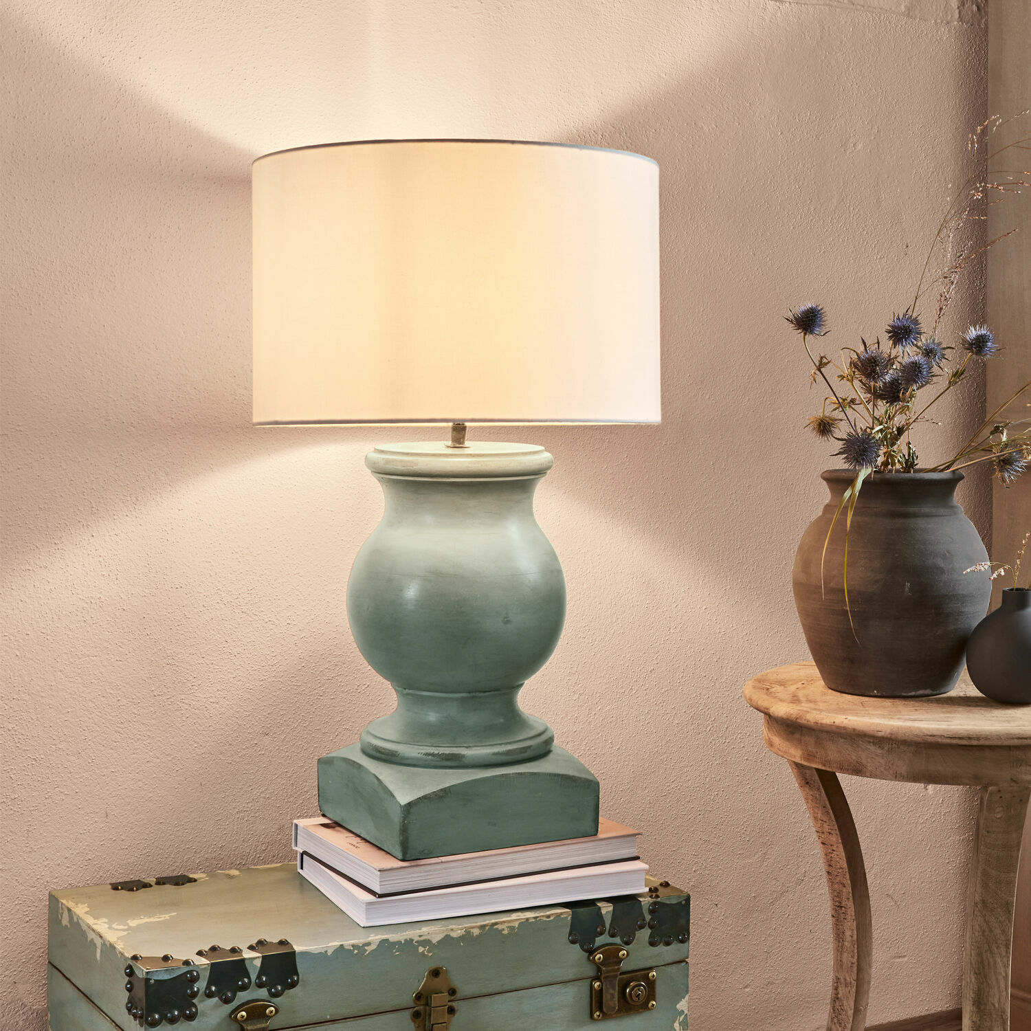 Tafellamp van groene keramiek met beige kap op een oude kist, interieurdecoratie