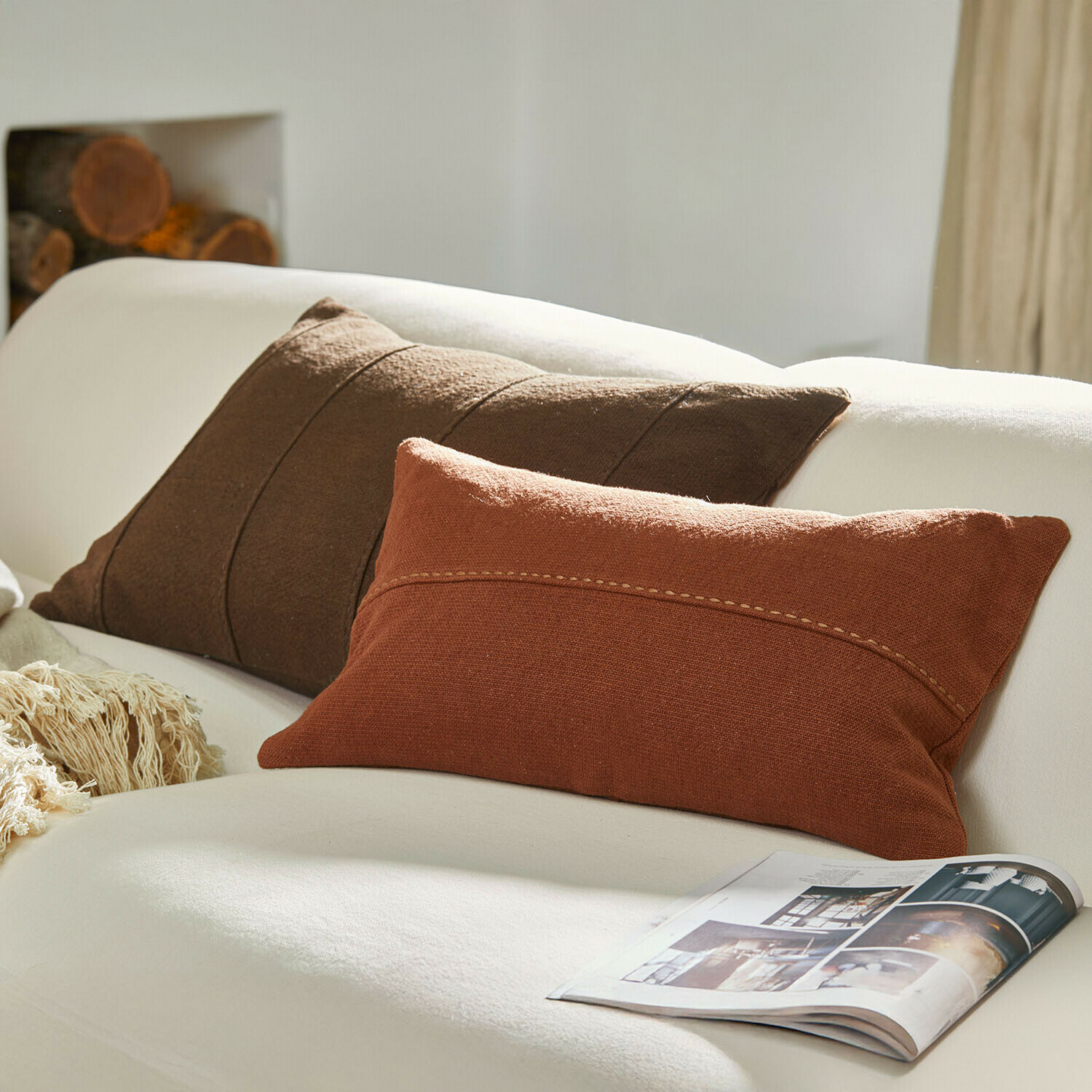 Coussins décoratifs marron et brique sur un canapé blanc avec un magazine, textiles pour salon