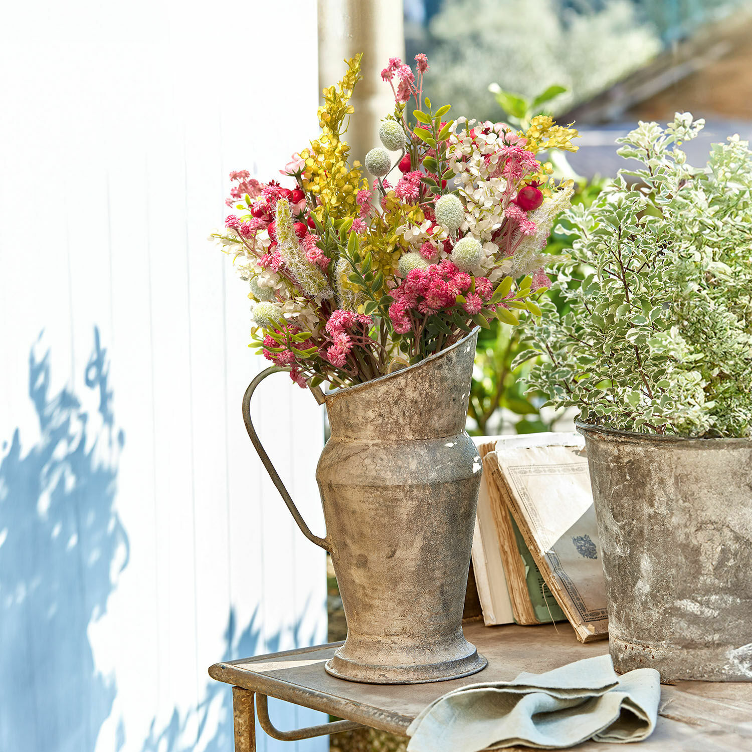 Metalen kan met kleurrijk droogboeket op houten tafel in tuin bij daglicht