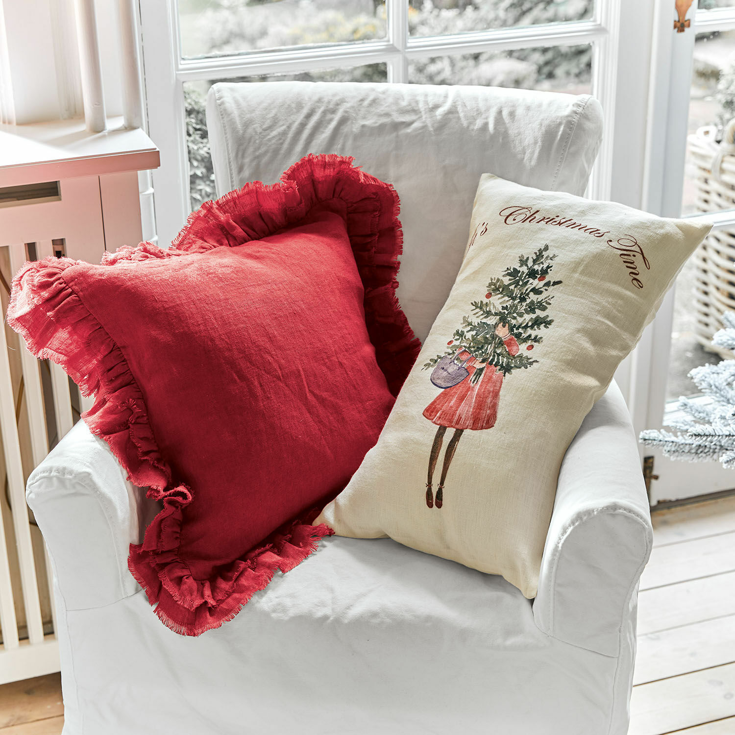 Kussenhoes set van 2 Christmas Time Twee decoratieve linnen kussens op een witte stoel, rood met ruches en crème met kerstmotief