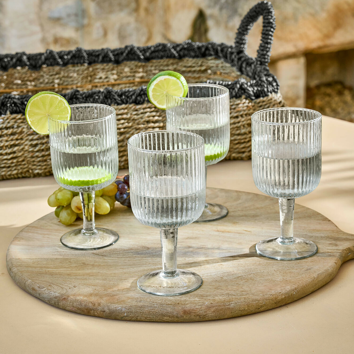 Lot de 4 verres Caleza Ensemble de quatre verres transparents en verre strié sur un plateau en bois avec des tranches de citron vert