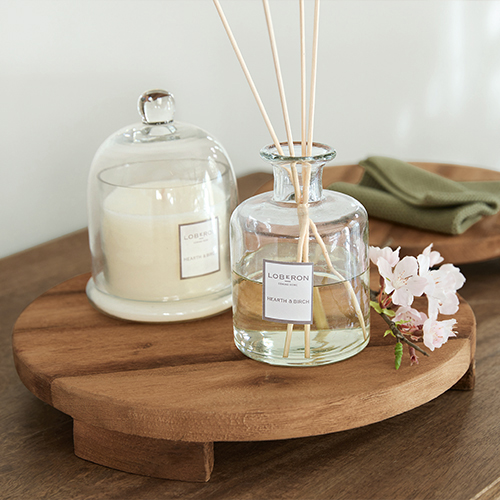 Ronde houten tray met doorzichtige geurverspreider en kaars onder glazen stolp, tafeldecoratie