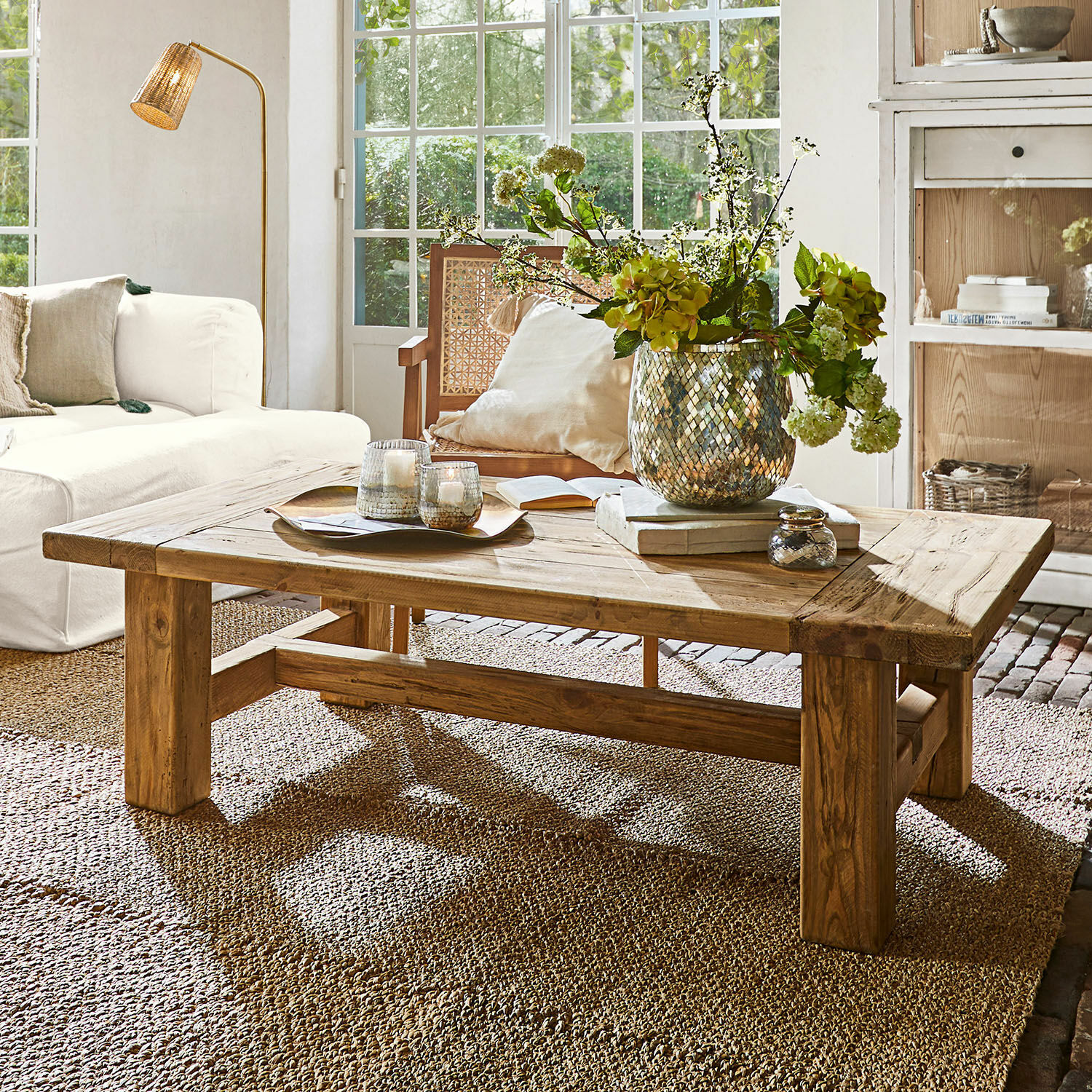 Table basse Oteley Table basse en bois naturel sur tapis dans un salon lumineux avec décoration florale