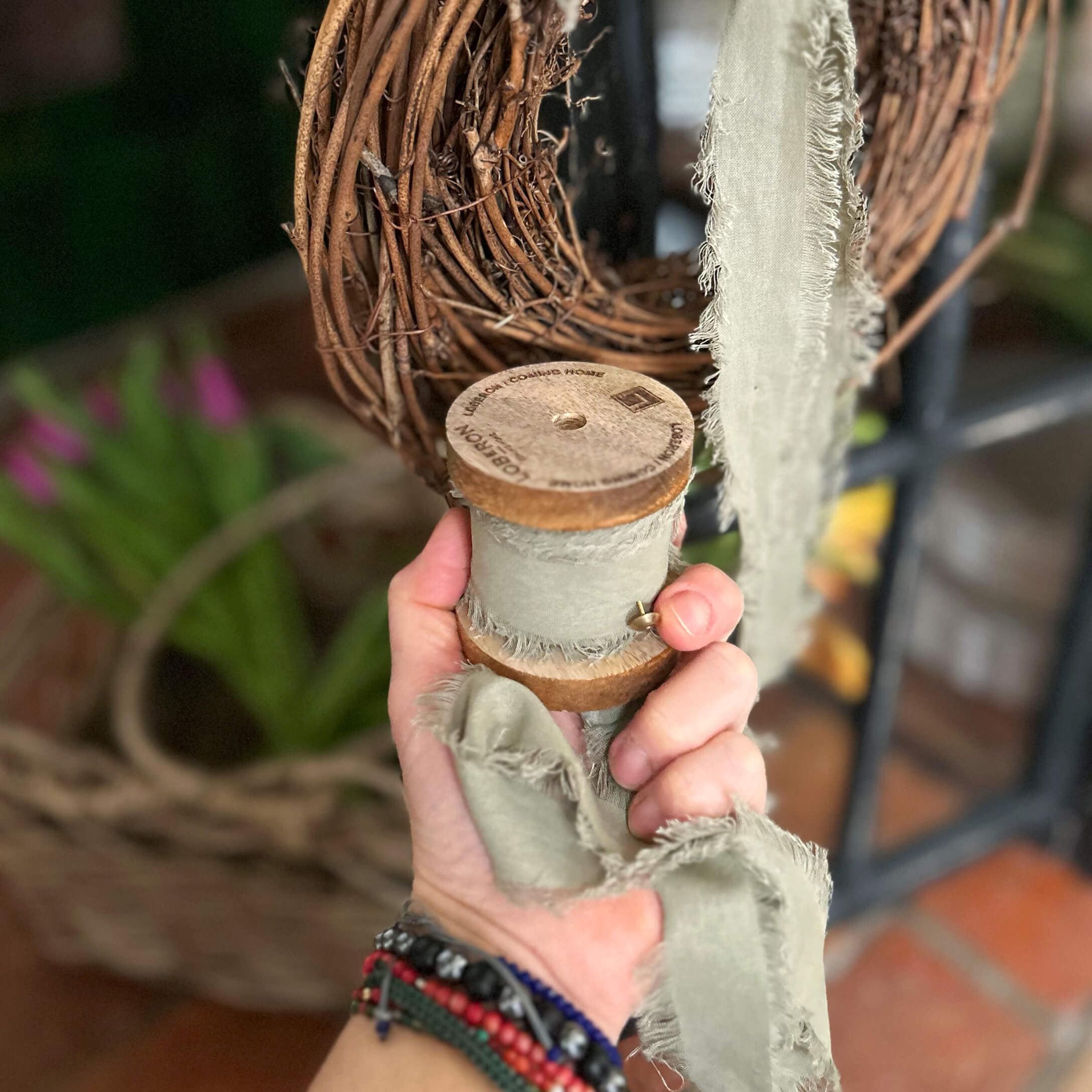 Grijze katoenen lint met rafelige randen op houten spoel voor decoratie en knutselen