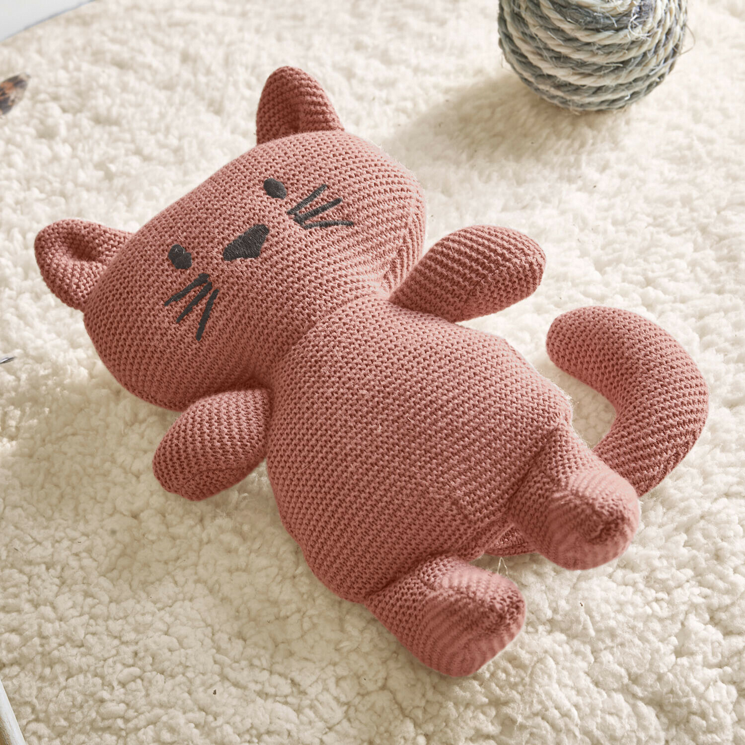 Hondenspeeltje Mewlie Roze gebreide katoenen kattenknuffel op wit zacht tapijt, kinderspeelgoed
