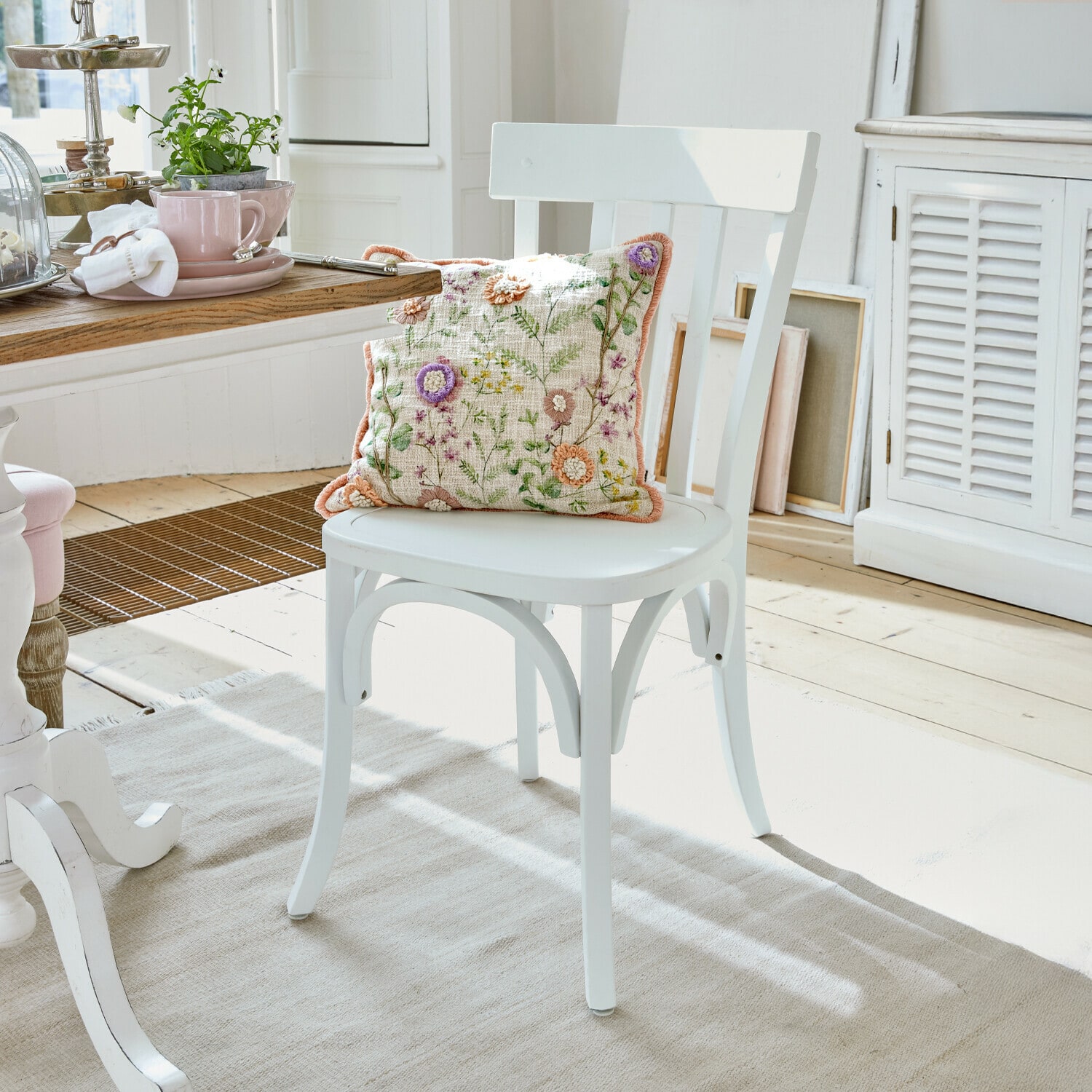 Chaise Passigny Chaise en bois blanc avec coussin brodé de fleurs dans une salle à manger lumineuse et élégante