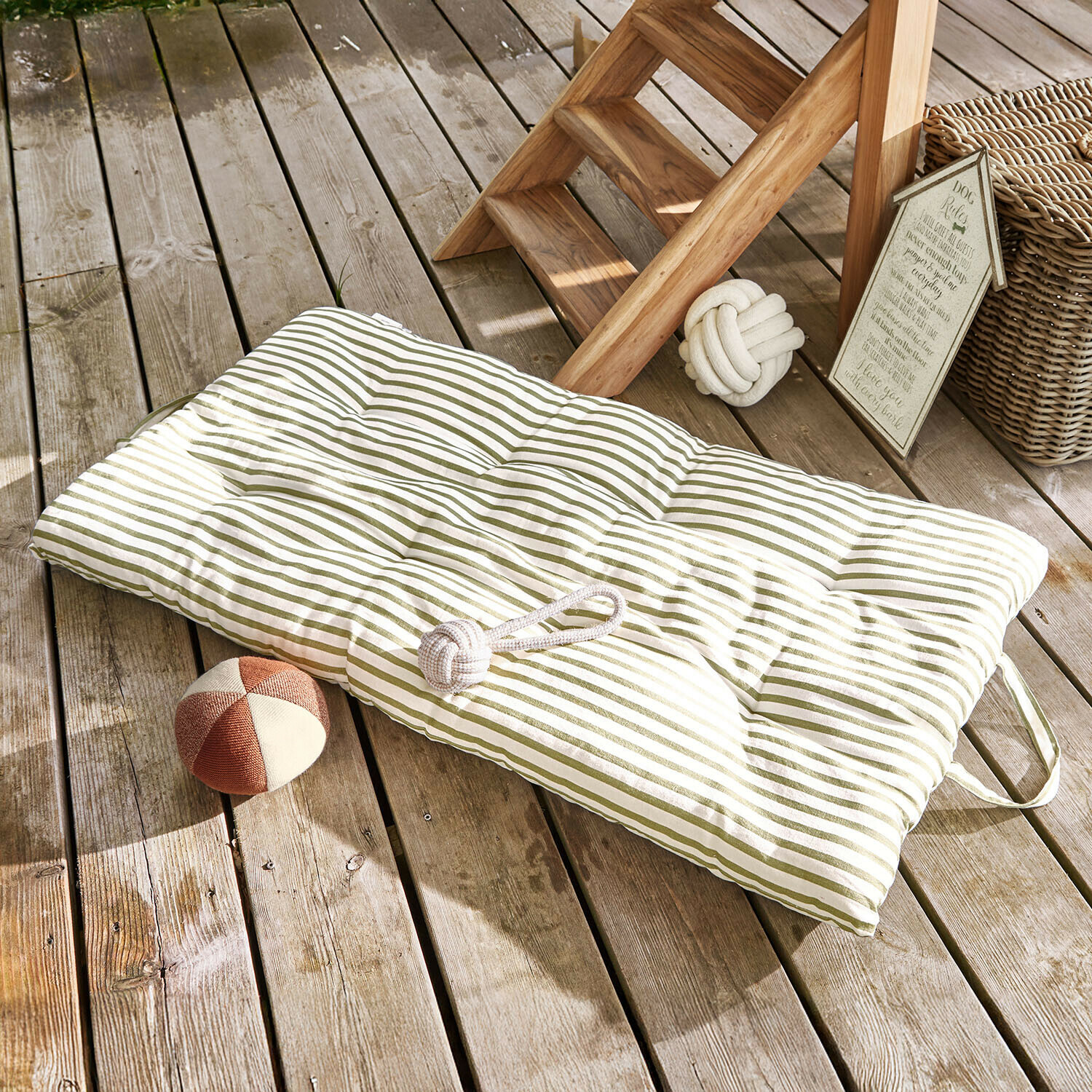 Coussin matelassé rayé vert pour sol en bois avec jouets pour chien à côté