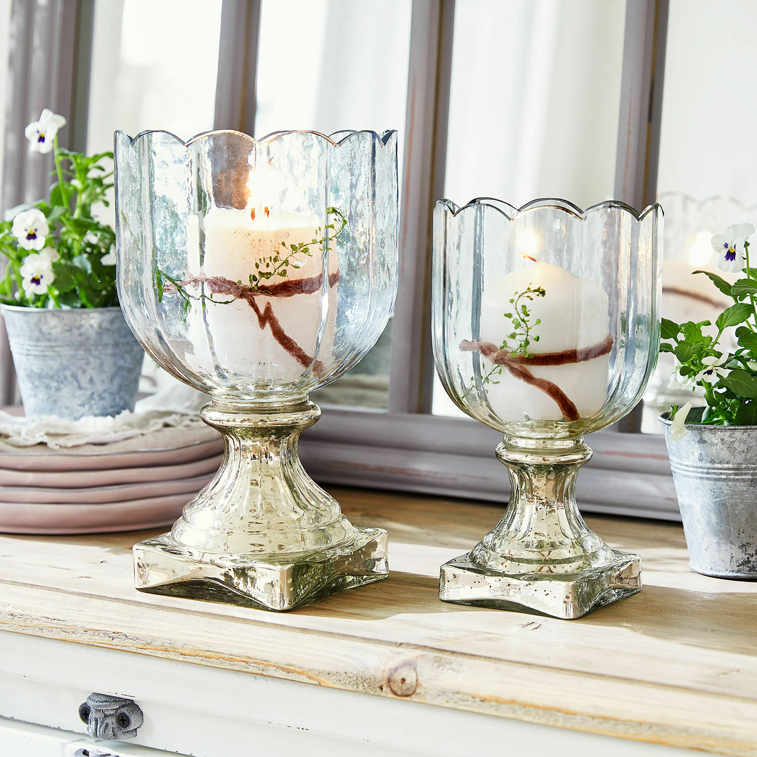Windlicht set van 2 Jovique Twee glazen kandelaren met witte kaarsen en plantenversiering op houten tafel