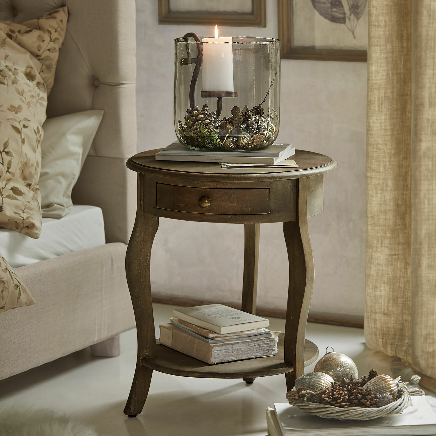 Bijzettafel Jace Ronde houten bijzettafel met lade en decoratieve glazen kandelaar met dennenappels