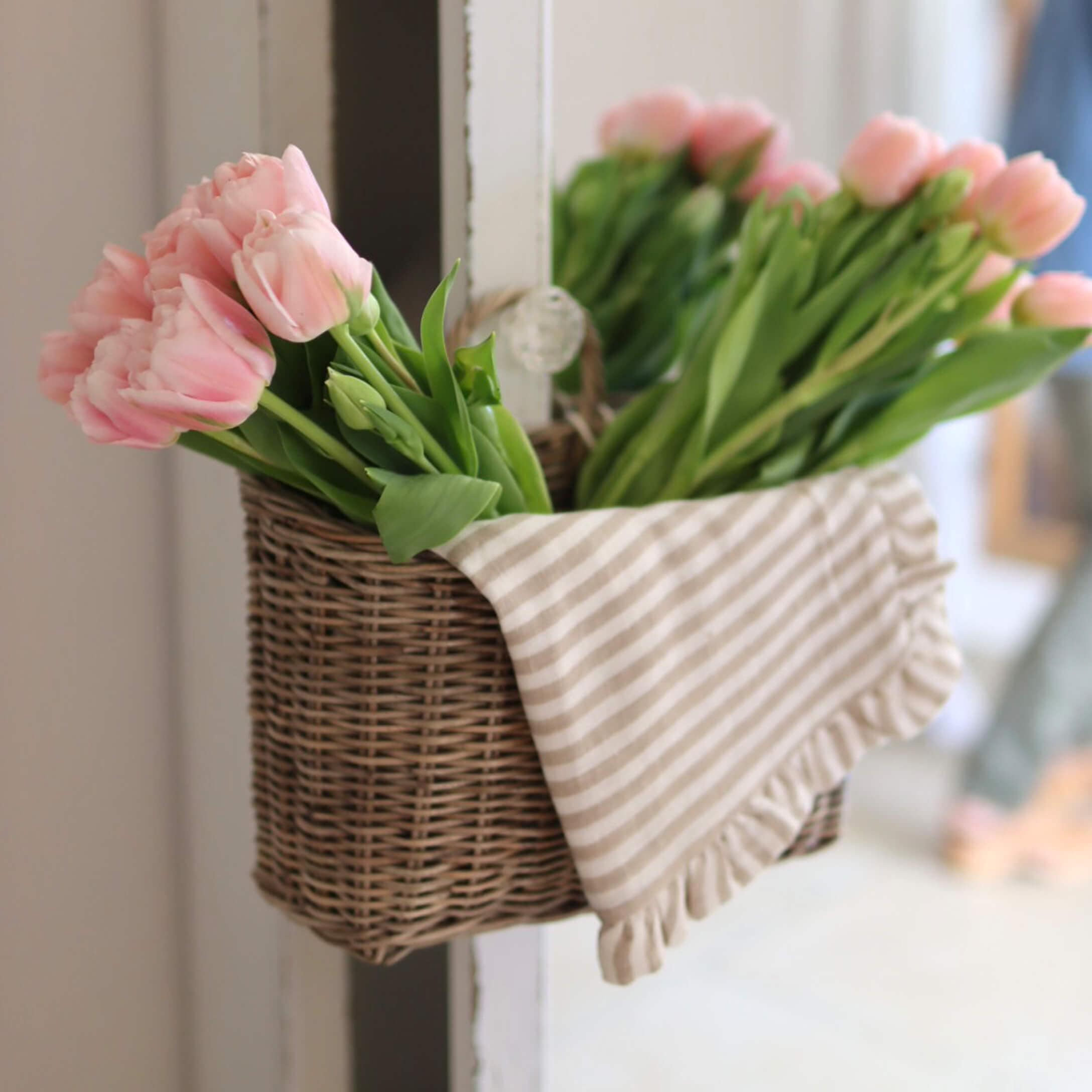 Panier en osier avec tulipes roses et torchon rayé en coton pour décoration intérieure