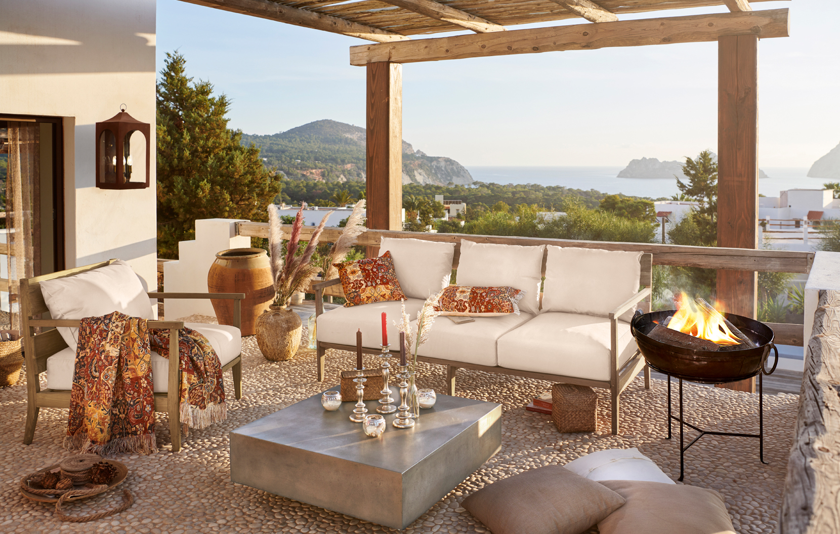 Terrasse confortable avec coussins beige et accessoires orientaux offrant vue sur mer et montagnes
