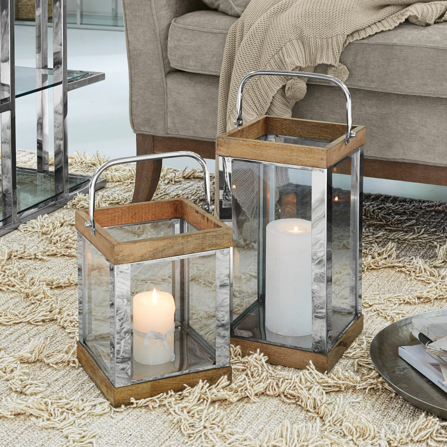 Twee lantaarns van hout en metaal met glazen wanden en witte kaarsen op een beige tapijt
