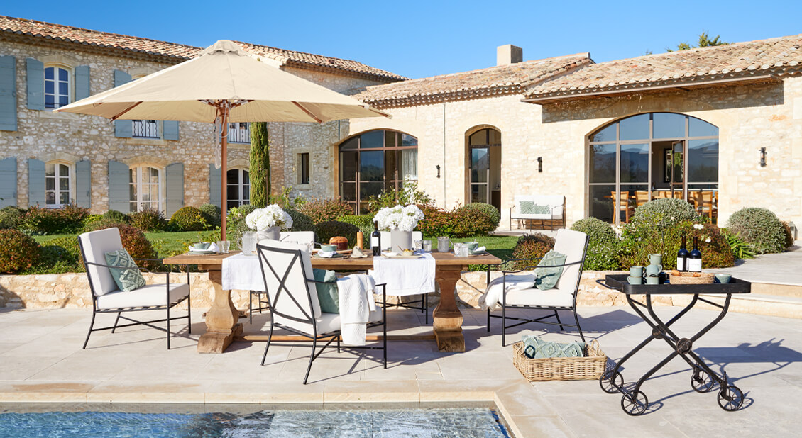 Ensemble de mobilier de jardin avec table en bois et coussins crème sur terrasse près de la piscine