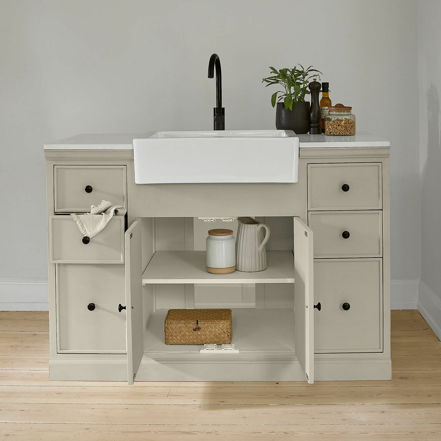 Meuble avec évier Orlévine Meuble de cuisine gris avec évier en céramique blanc et robinet noir, portes ouvertes avec étagères visibles