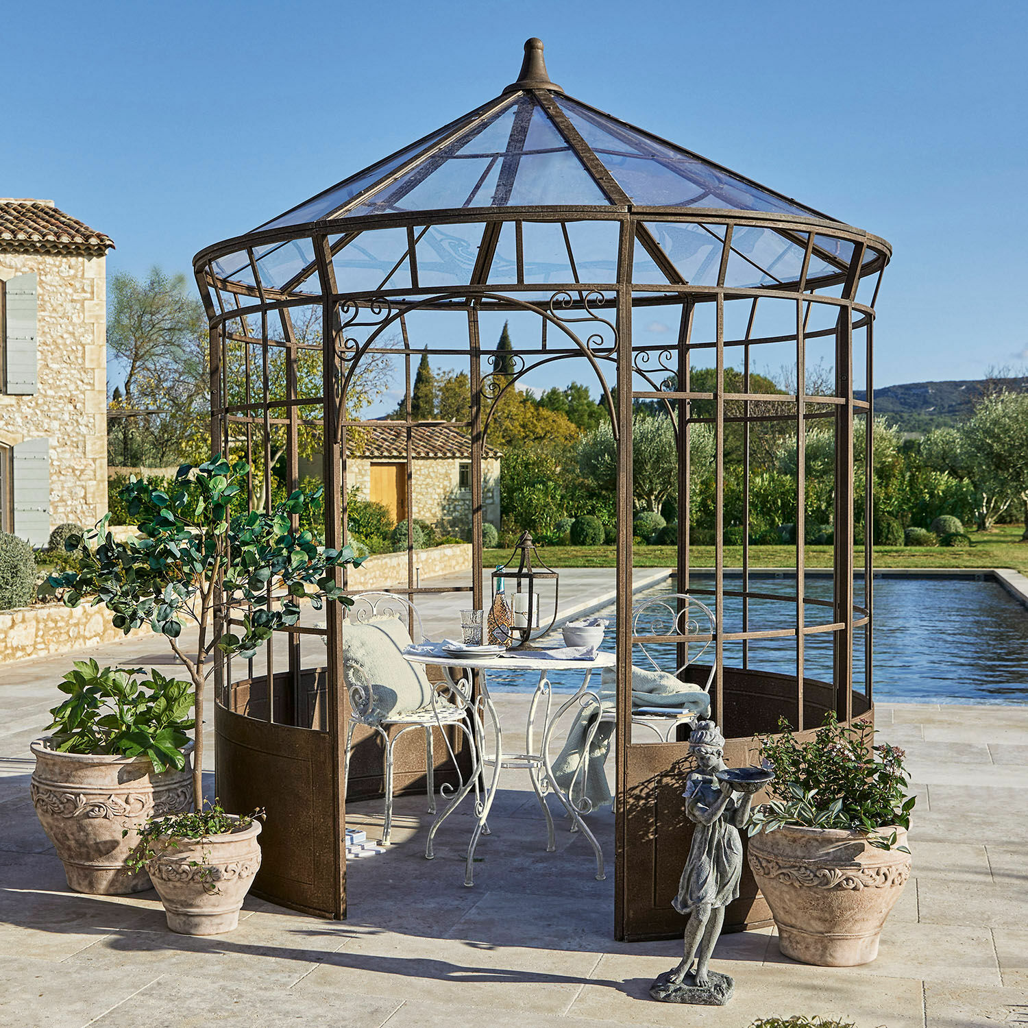 Gloriette Murillo Kiosque de jardin en métal couleur rouille avec table blanche et chaises sur terrasse près de la piscine