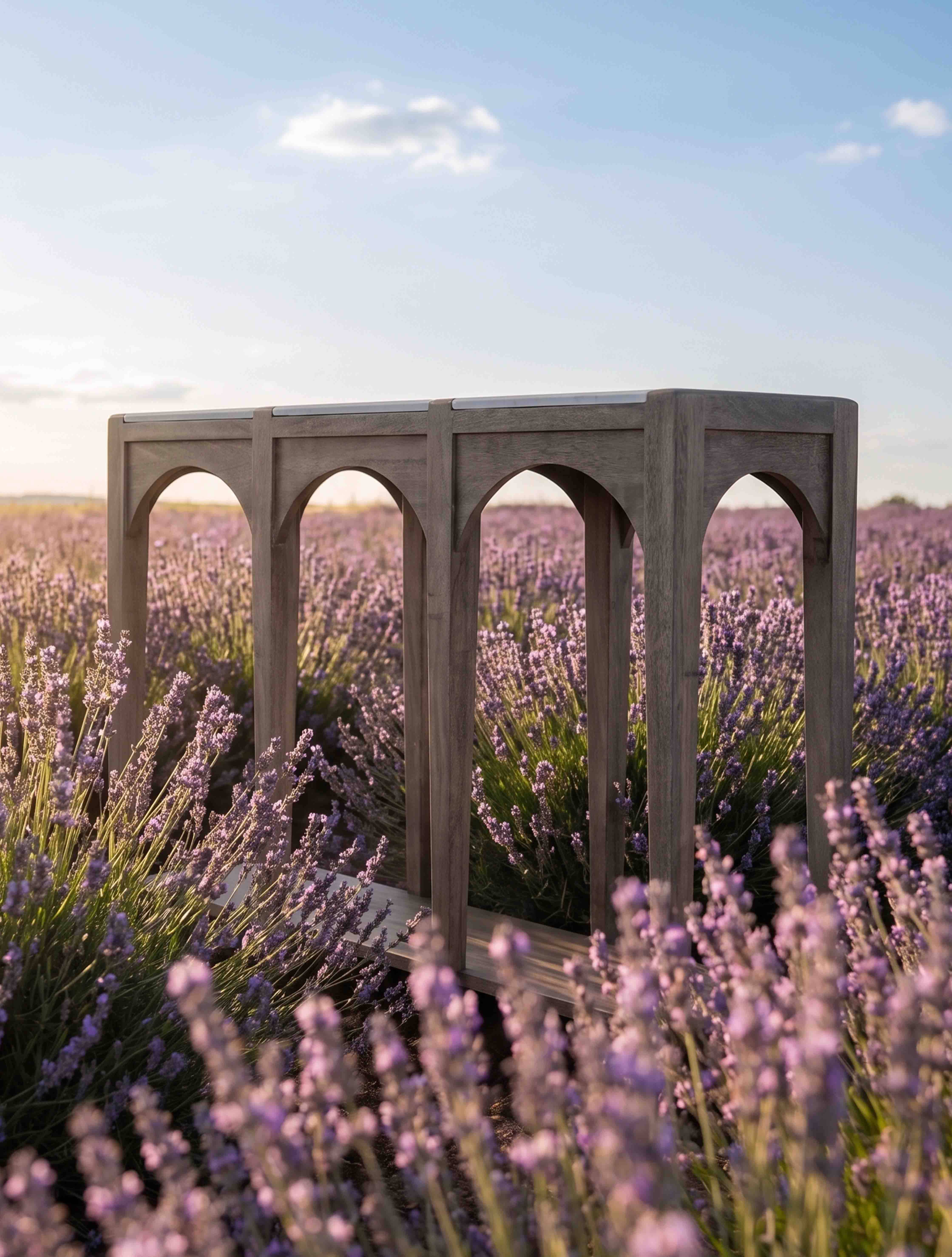 Grijze houten tuintafel met gebogen poten tegen een achtergrond van paarse lavendelvelden