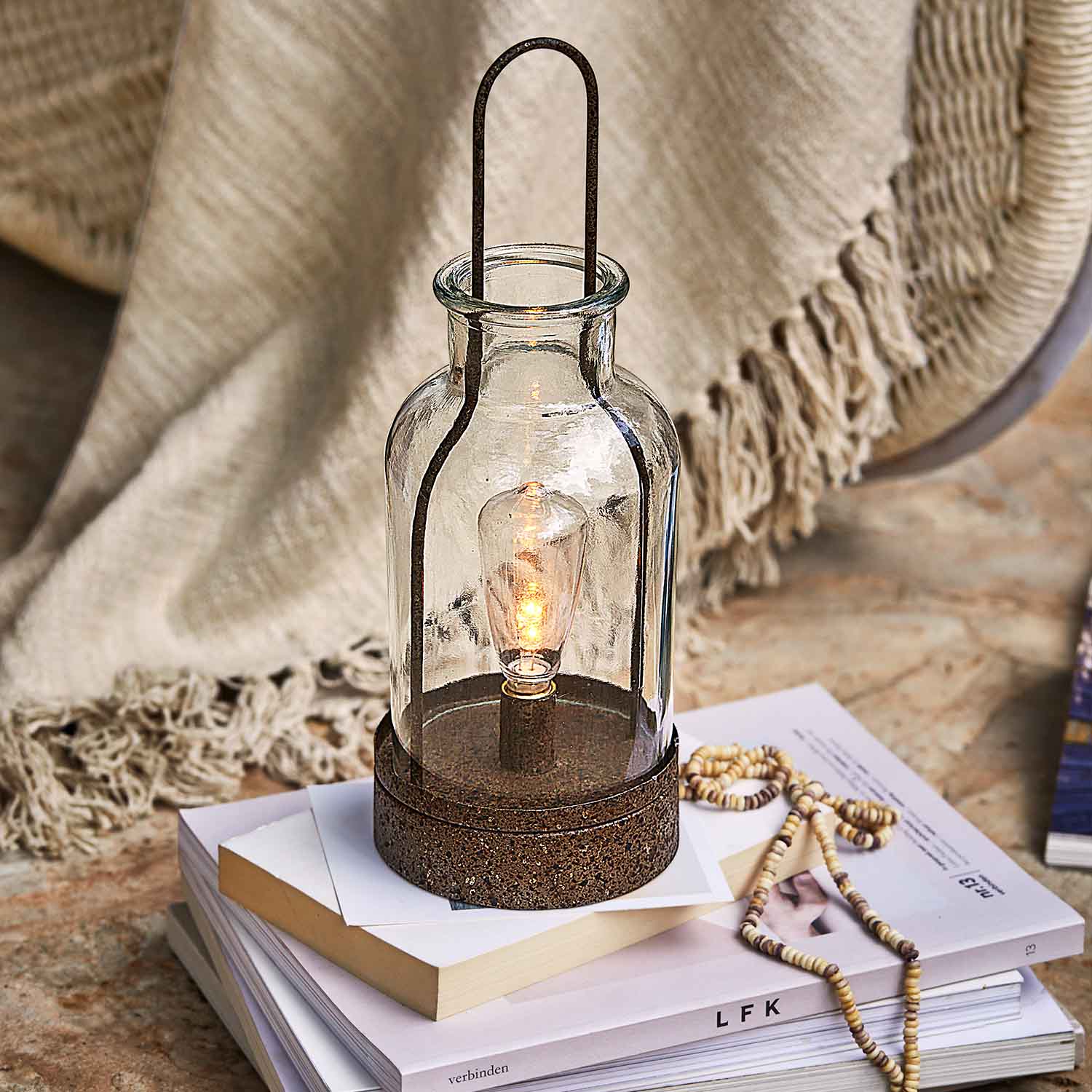 Lanterne en verre avec base métallique rouillée posée sur des livres, décoration intérieure et éclairage