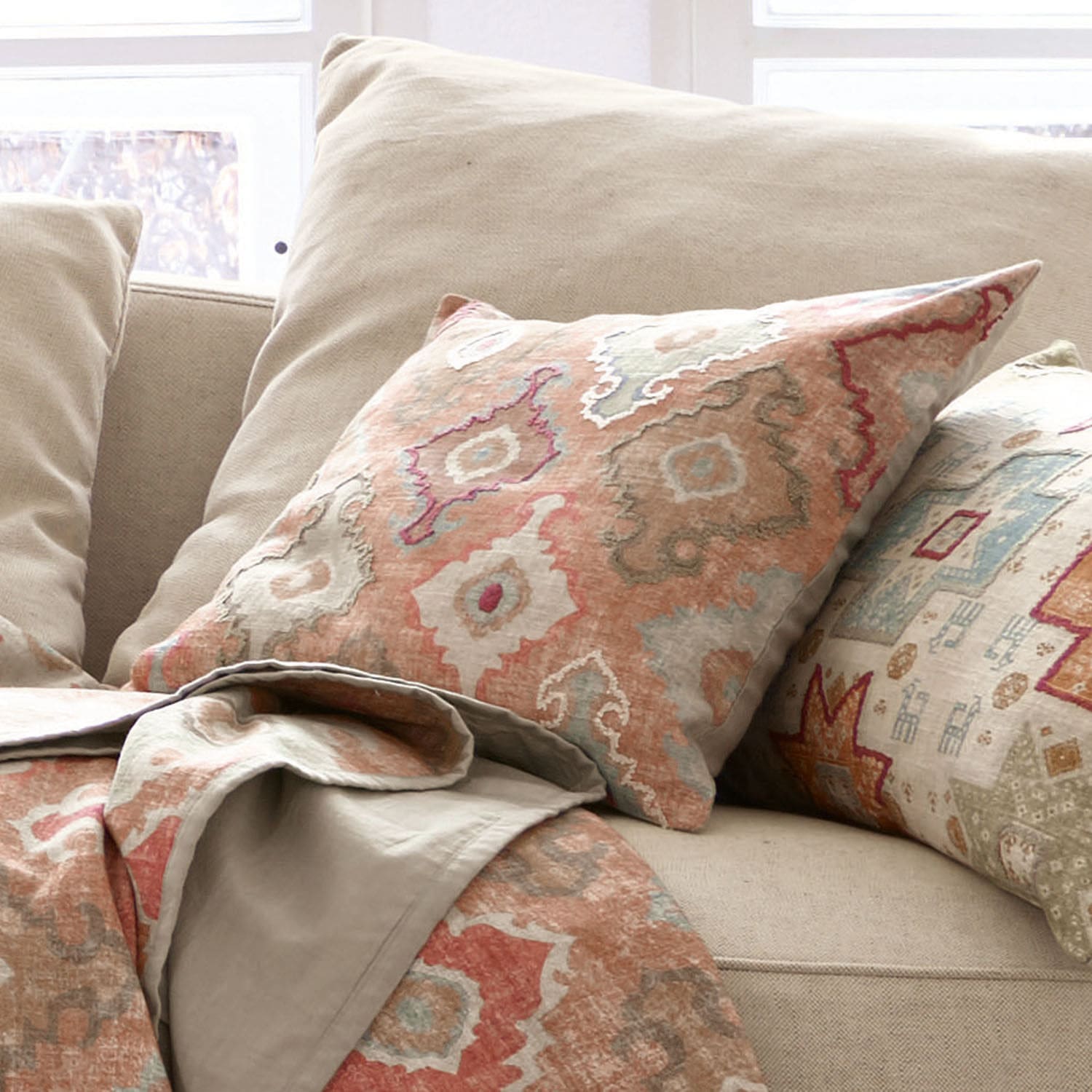 Beige bank met decoratief kussen en deken met warme geometrische patronen