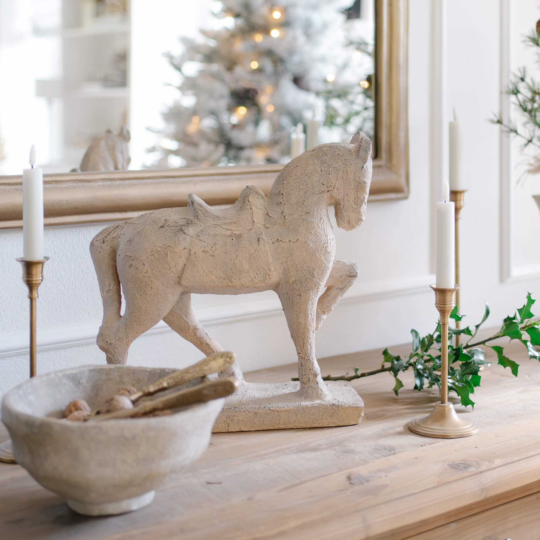 Sculpture décorative de cheval en matériau pierreux beige sur une table en bois avec bougies