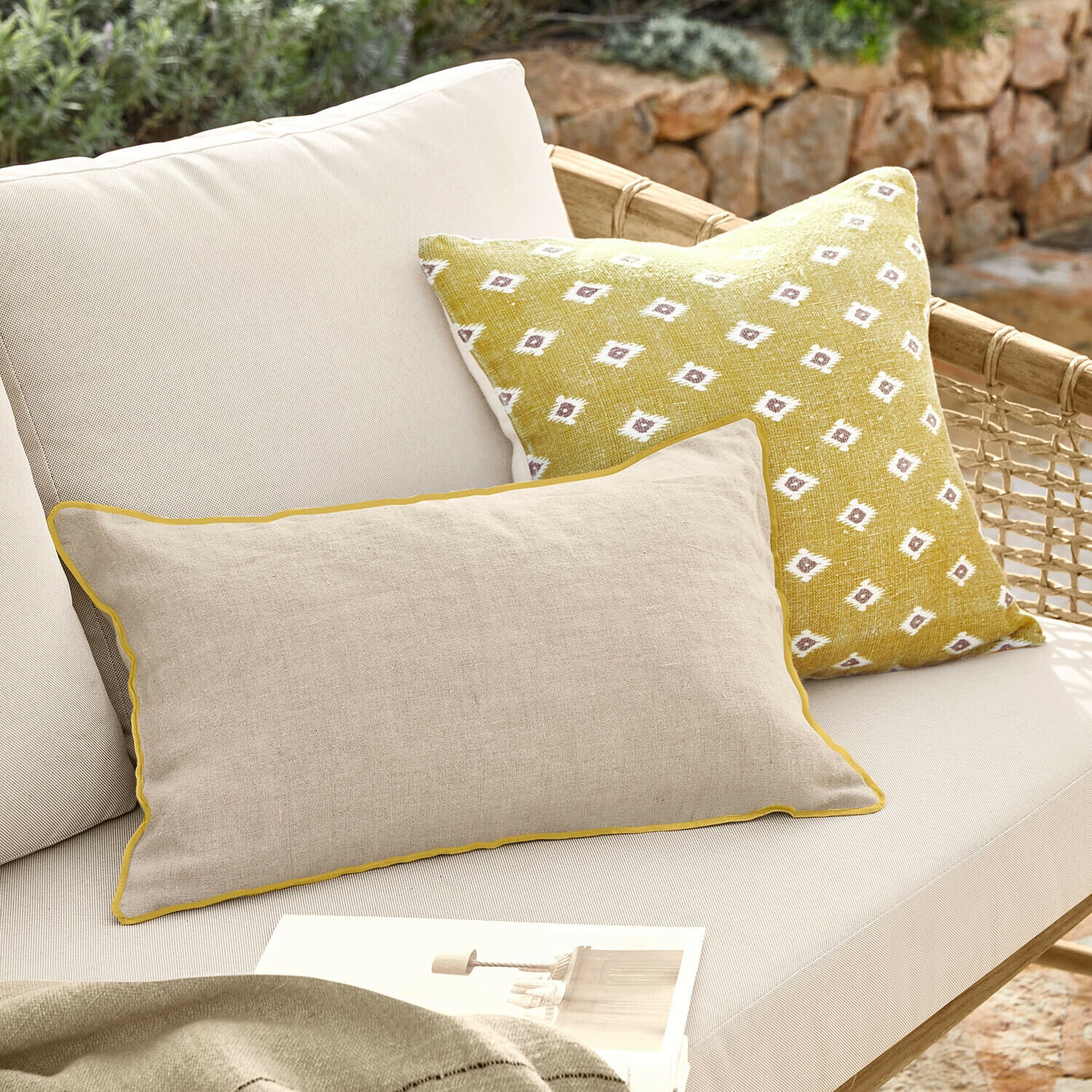Kussenhoes set van 2 Brisalda Beige linnen kussen met gele bies en geel kussen met wit patroon op lichte loungesofa buiten