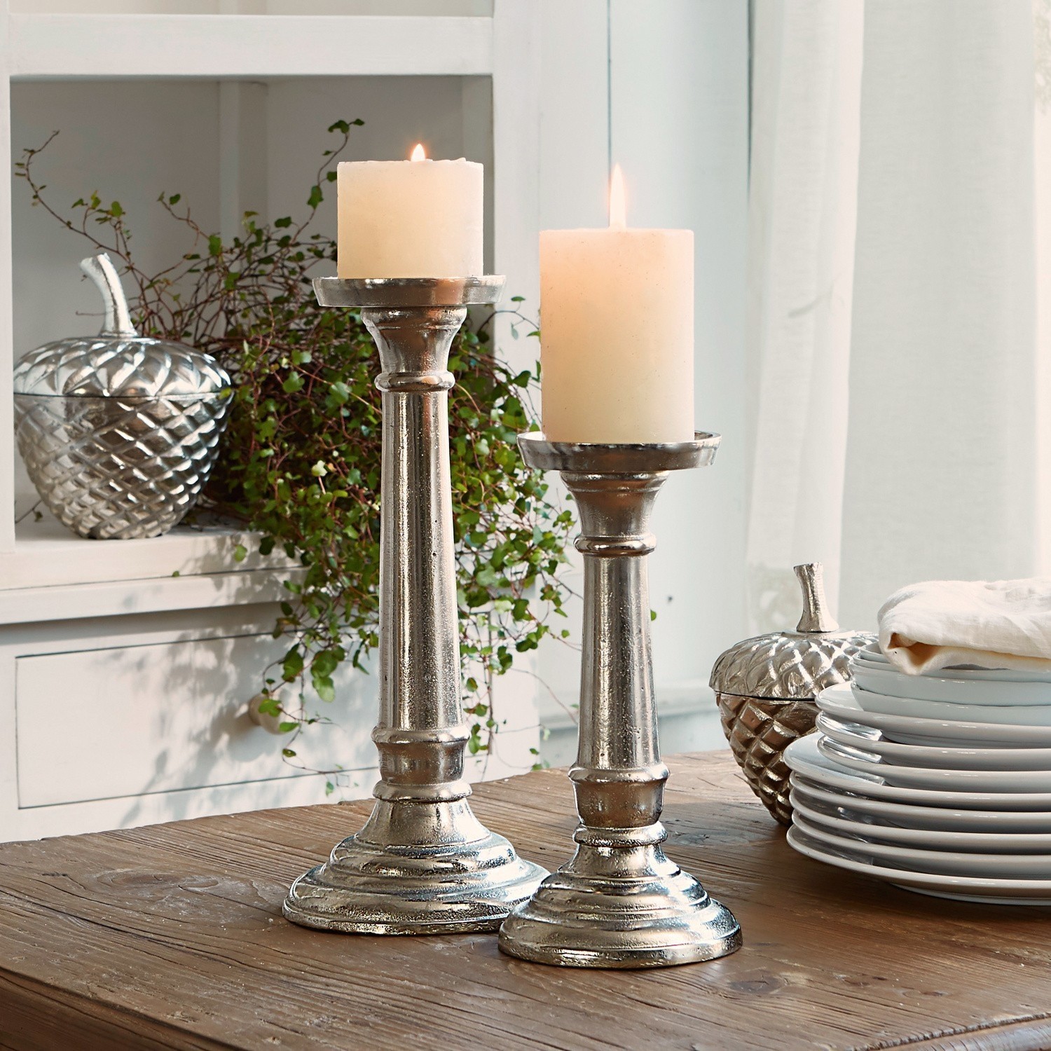 Kandelaar set van 2 Symone Twee zilverkleurige metalen kandelaars met witte kaarsen op houten tafel voor interieurdecoratie