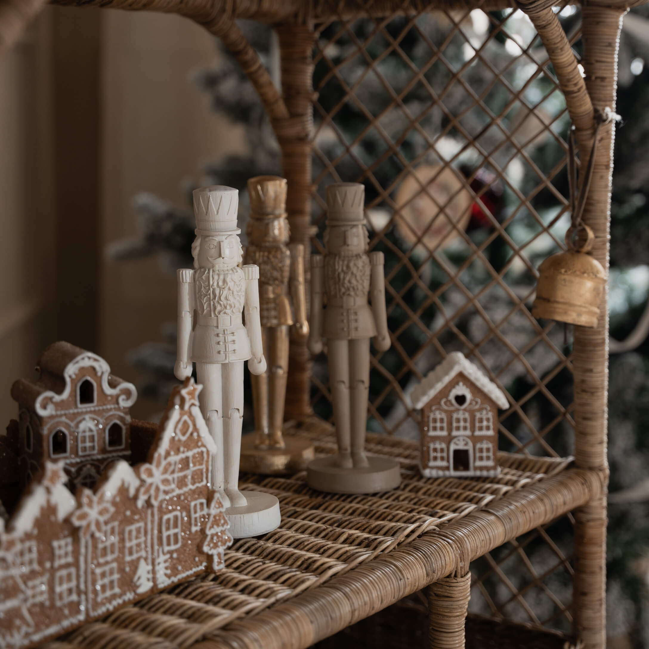 Figurines en bois de soldats blancs et beige sur une étagère en osier avec maisons en pain d'épice