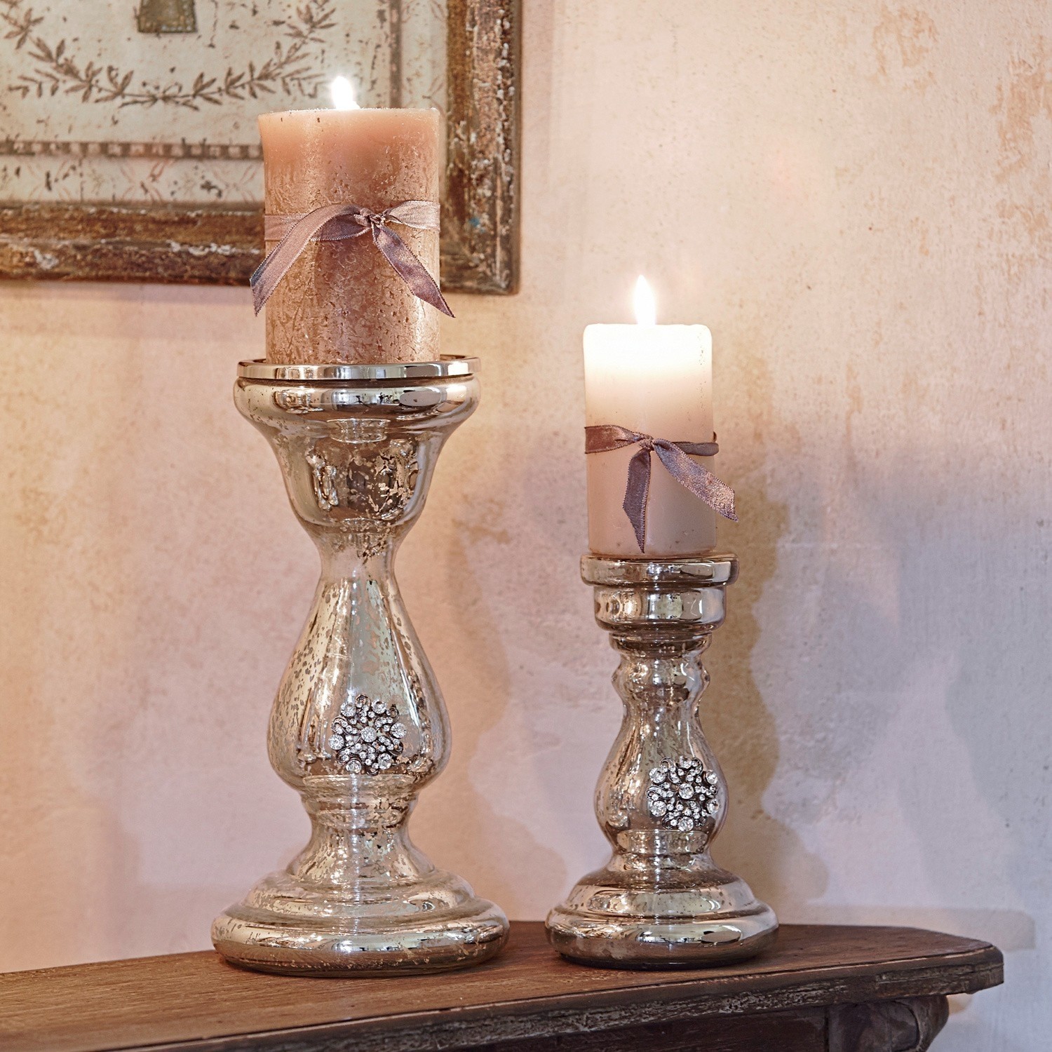 Kandelaar set van 2 Lysiane Twee zilveren kandelaars met decoratieve kristallen en beige kaarsen met strikjes op houten tafel