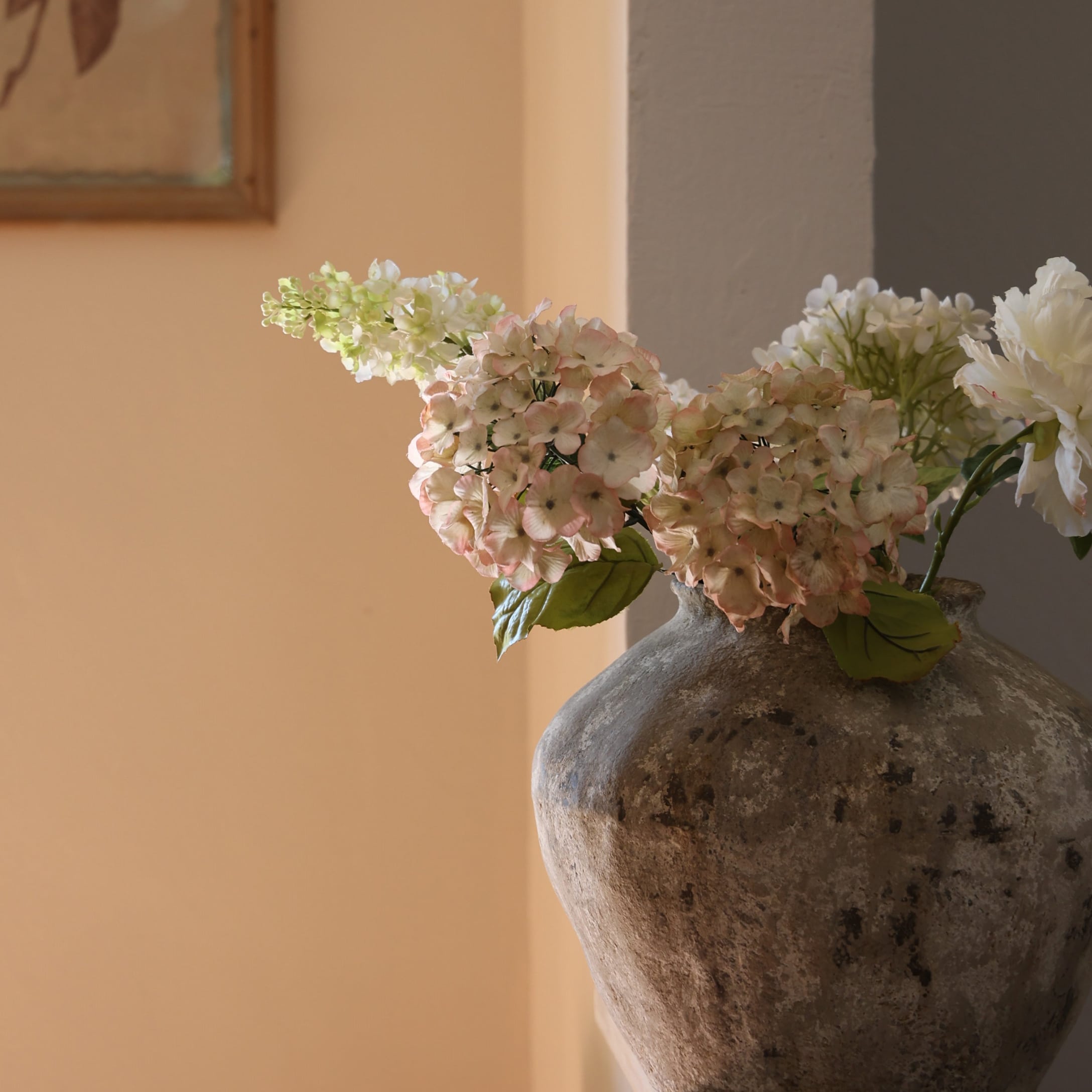 Vase rustique en pierre avec fleurs délicates aux tons pastel pour décoration intérieure élégante