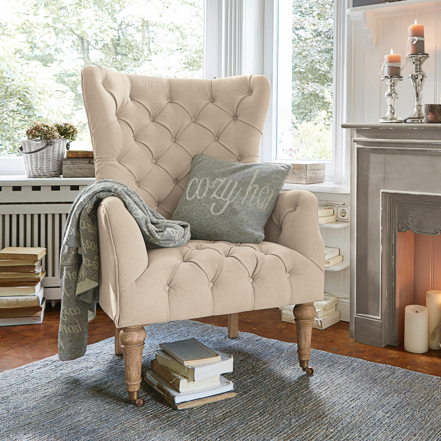 Fauteuil Migré Beige gestoffeerde fauteuil met knopen en houten poten in gezellige woonkamer bij open haard
