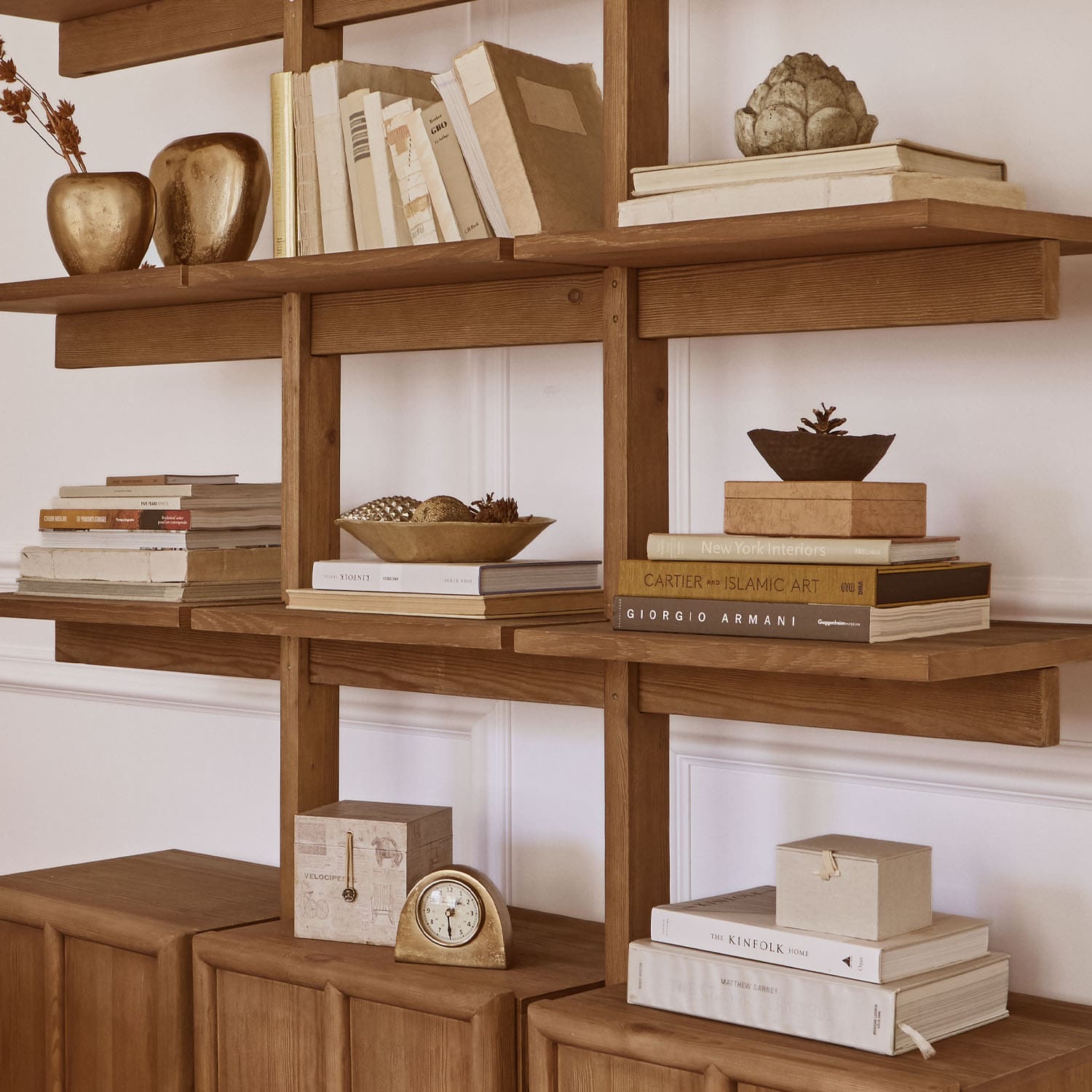 Houten kast met boeken, gouden decoraties en klok, stijlvolle interieurinrichting