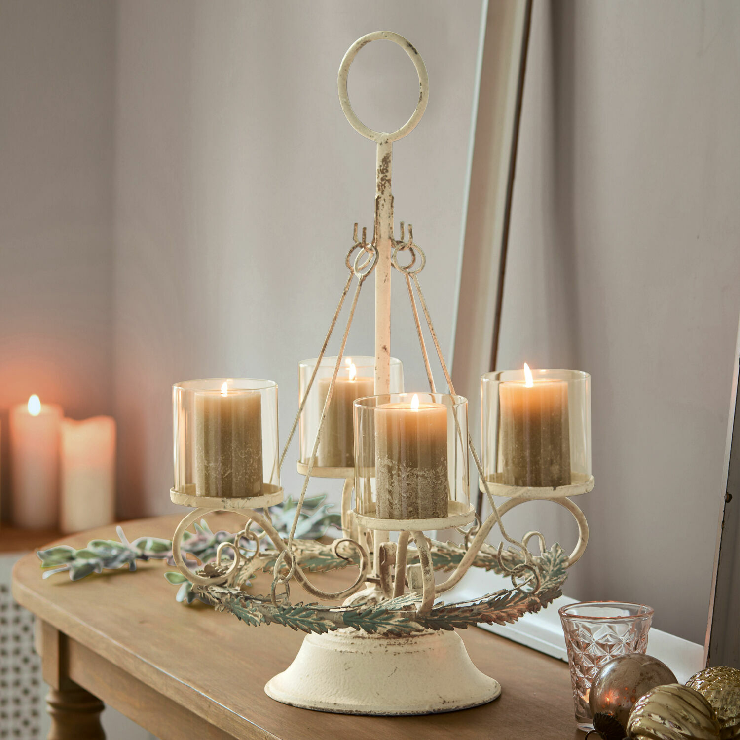 Vintage metalen kandelaar in crèmekleur met vier beige kaarsen op houten tafel, woondecoratie